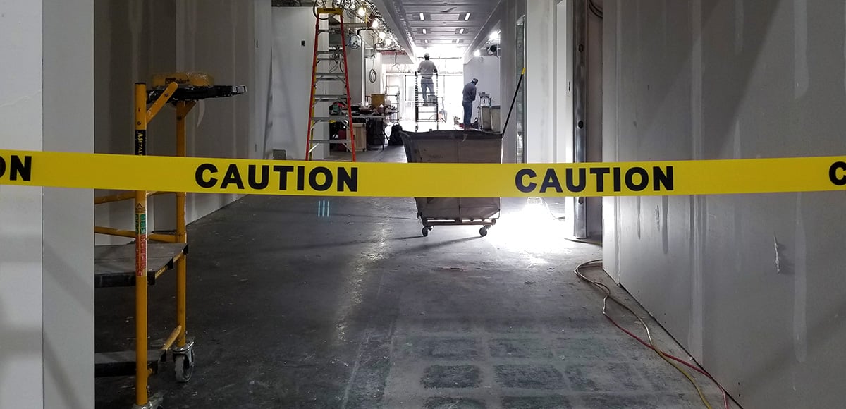 BannerStakes caution banner with workers in hallway