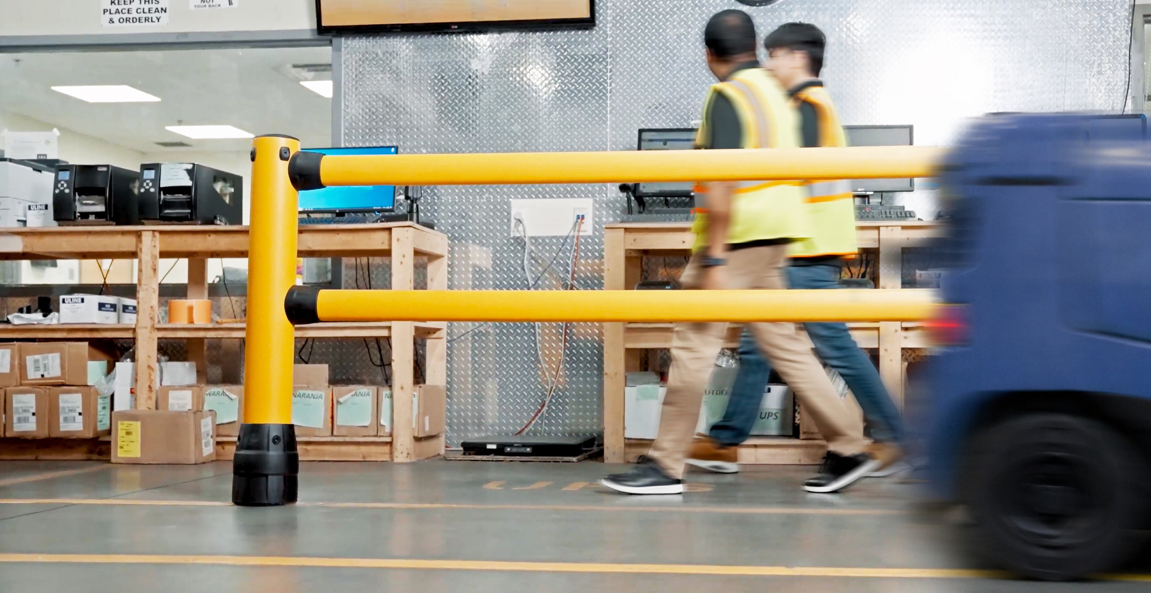 Workers protected by McCue FLEX+ pedestrian guardrail as vehicle passes in distribution center aisle