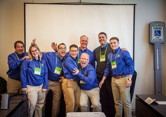 McCue employees group photo in front of projector screen