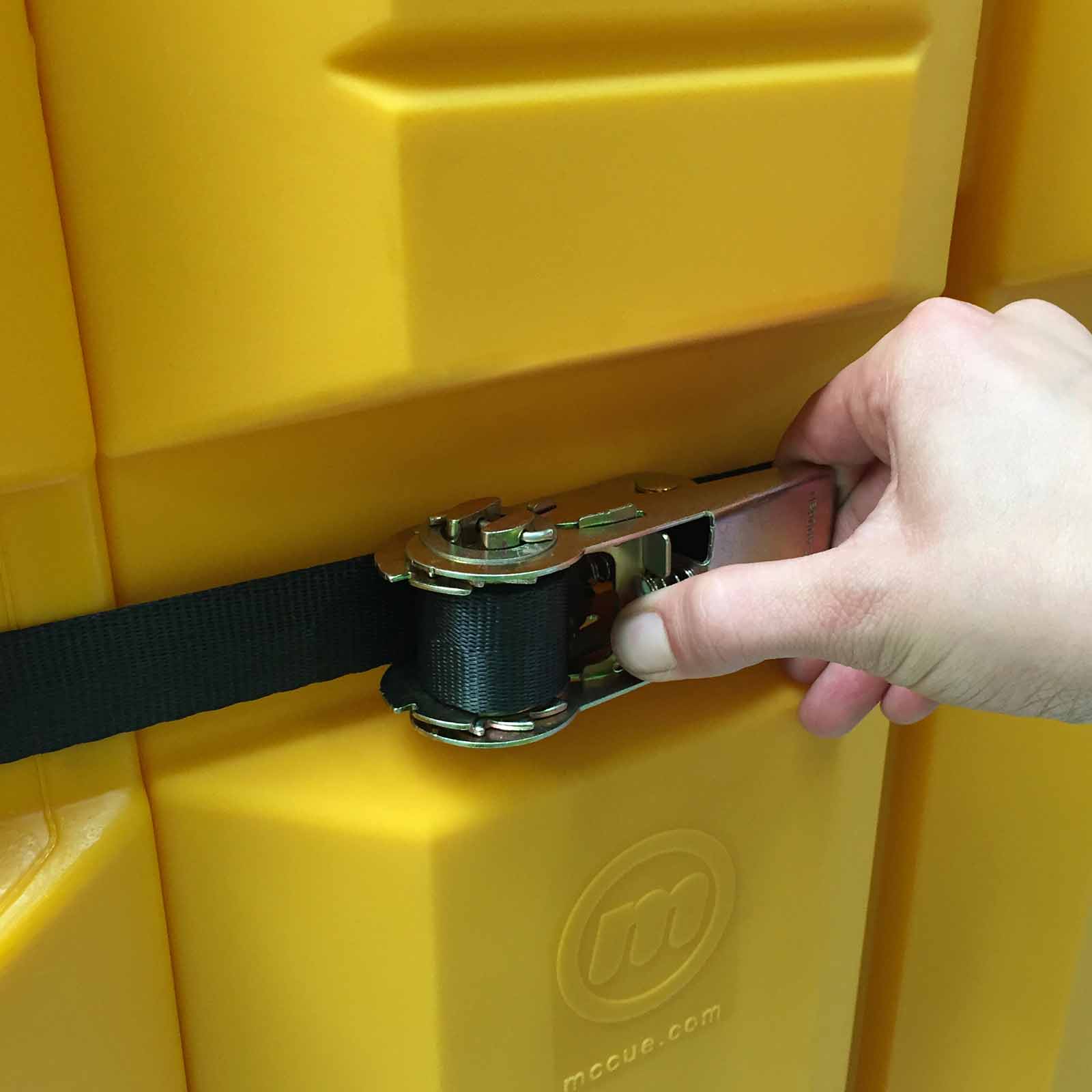 Hand tightening the ratchet strap that holds a ColumnGuard in place on a warehouse column.