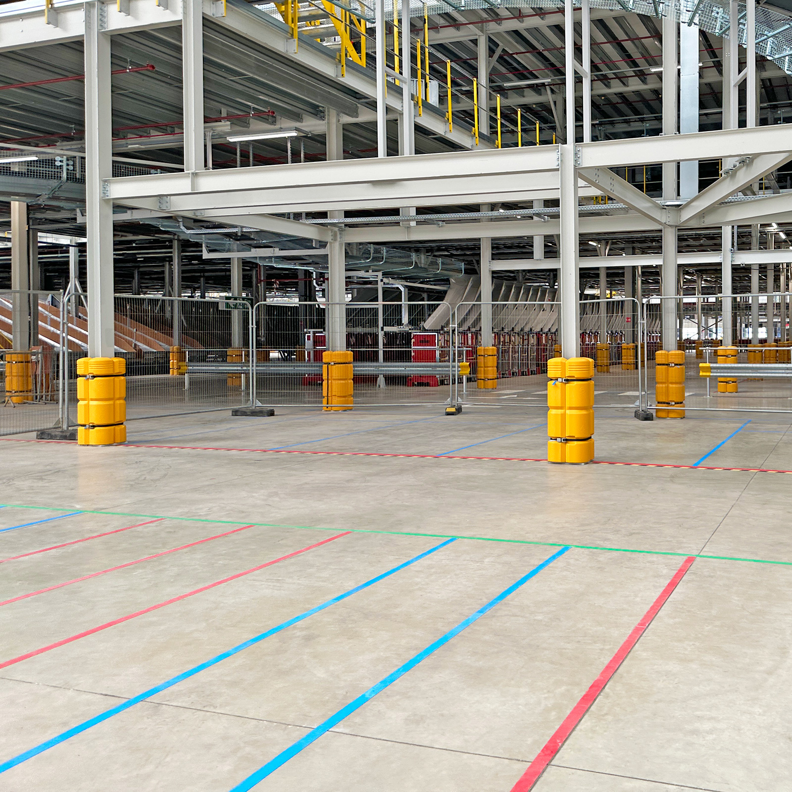 Row of ColumnGuards on steel columns across an open distribution center floor with blue and red lanes.