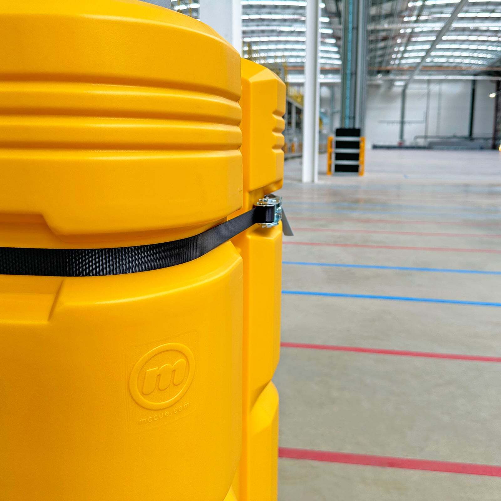 Close-up of a ColumnGuard for warehouse columns, with its black ratchet strap and floor lanes behind.