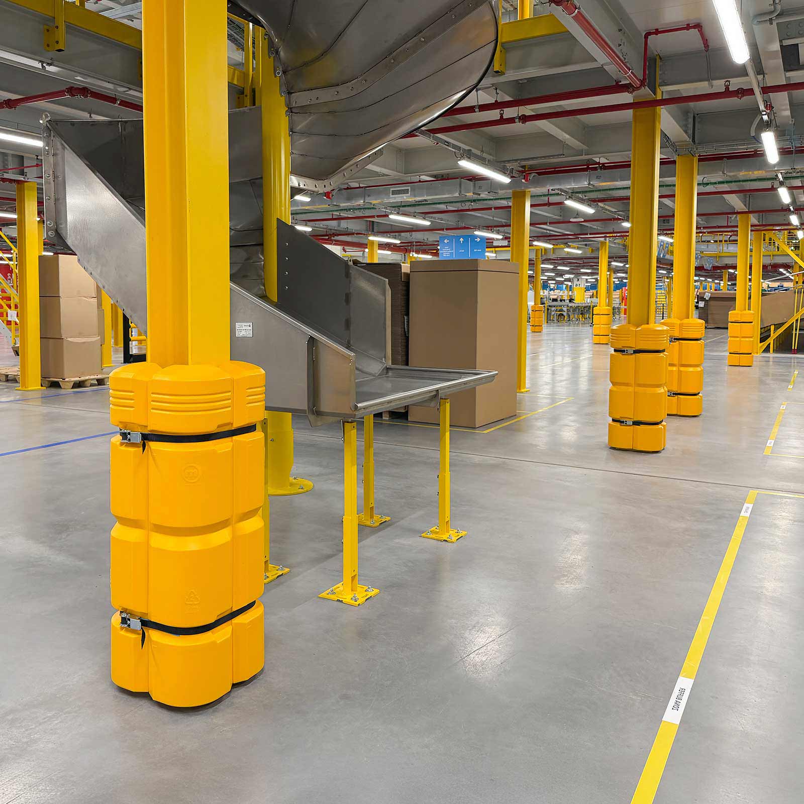 ColumnGuard protecting a steel column beneath a spiral conveyor chute in a fulfillment center.