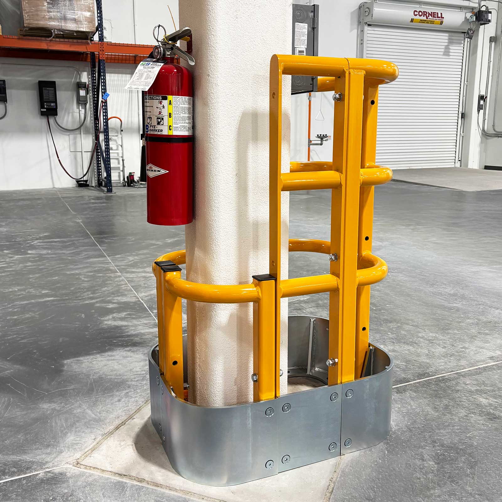 ColumnProtector around a white column with a mounted fire extinguisher, near a roll-up door in an industrial space.