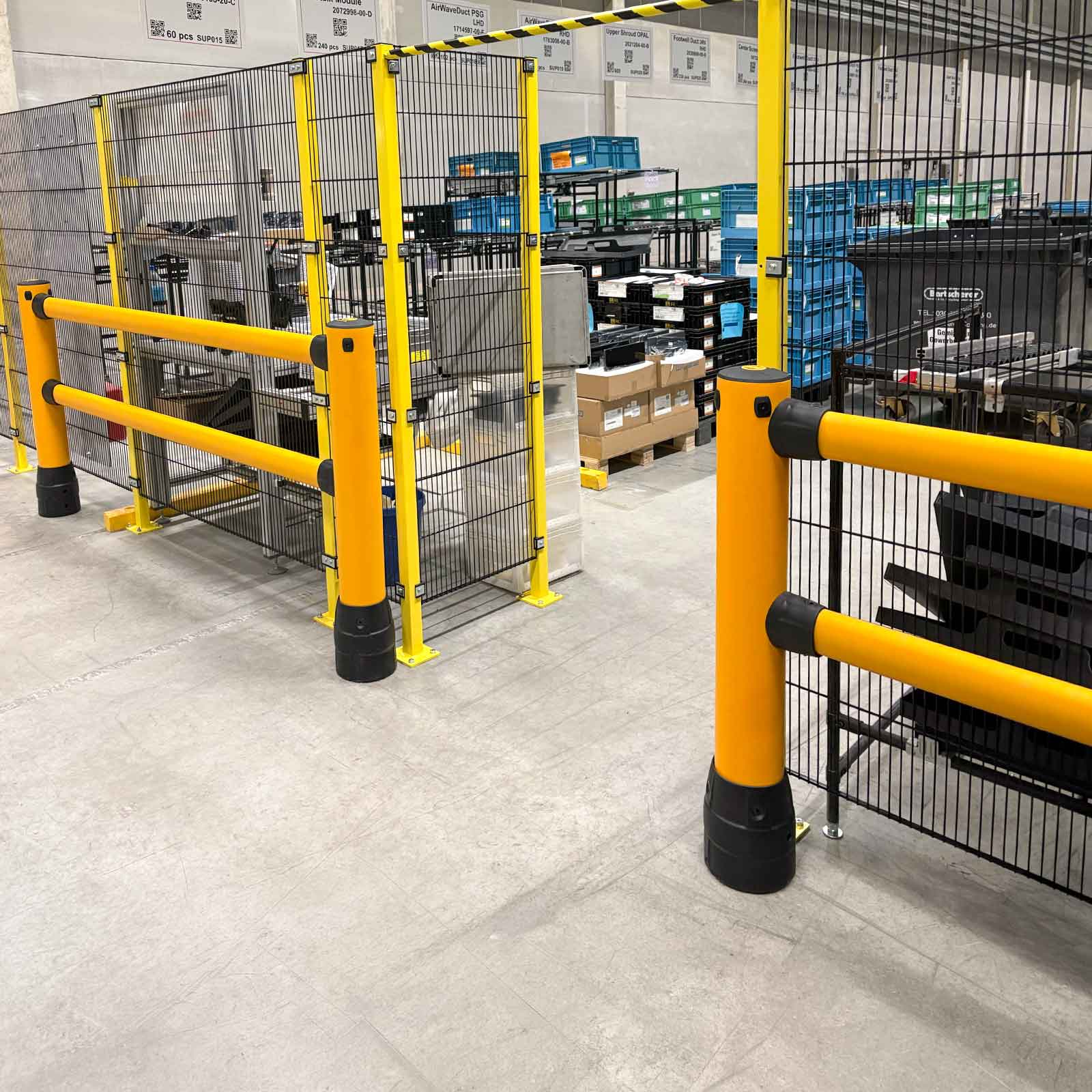 FLEX+ Pedestrian Guard corner run in front of mesh-fenced equipment enclosures and stacked plastic bins on a plant floor.