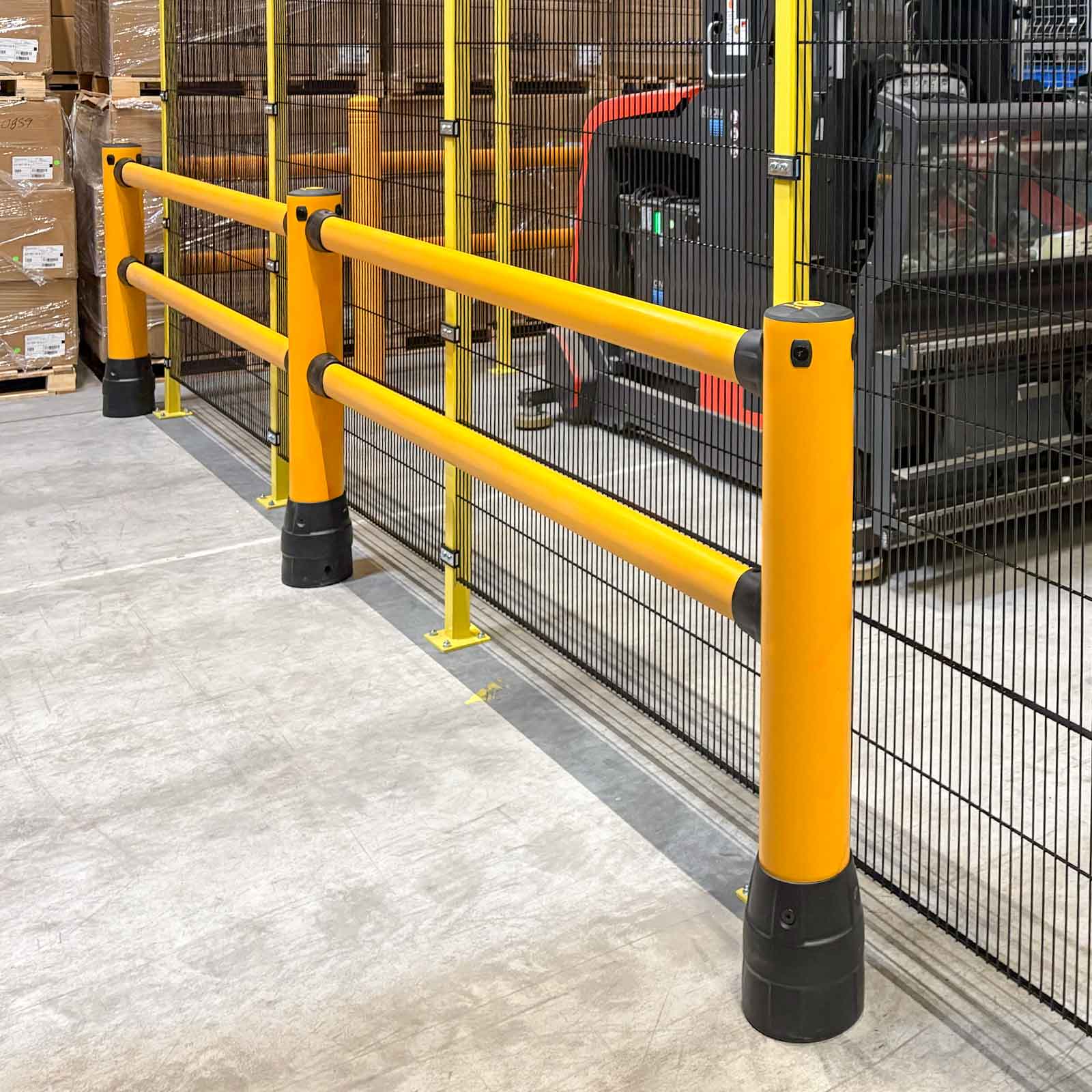 FLEX+ Pedestrian Guard running along a mesh machine-guarding fence on a warehouse floor, with a forklift behind the mesh.