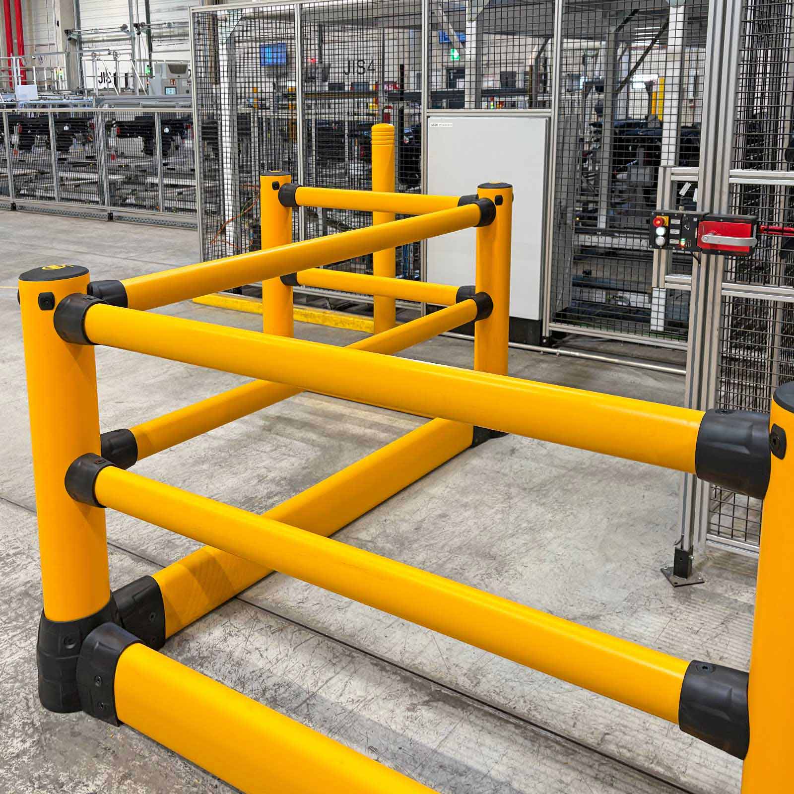 FLEX+ Pedestrian with Ground Guard corner section guarding caged production machinery on a manufacturing floor.