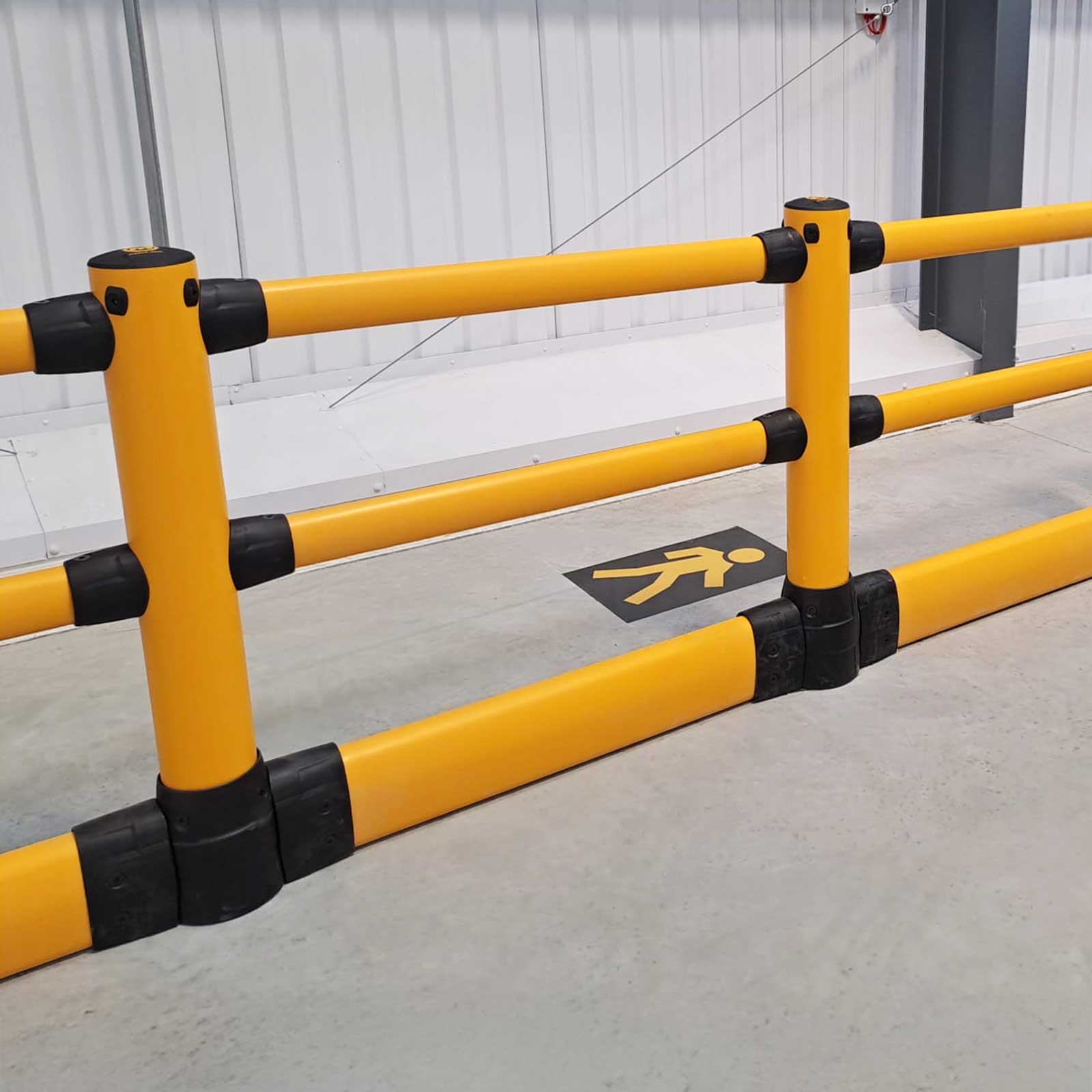 Close-up of FLEX+ Pedestrian with Ground Guard posts and rails beside a pedestrian floor marking in a warehouse.