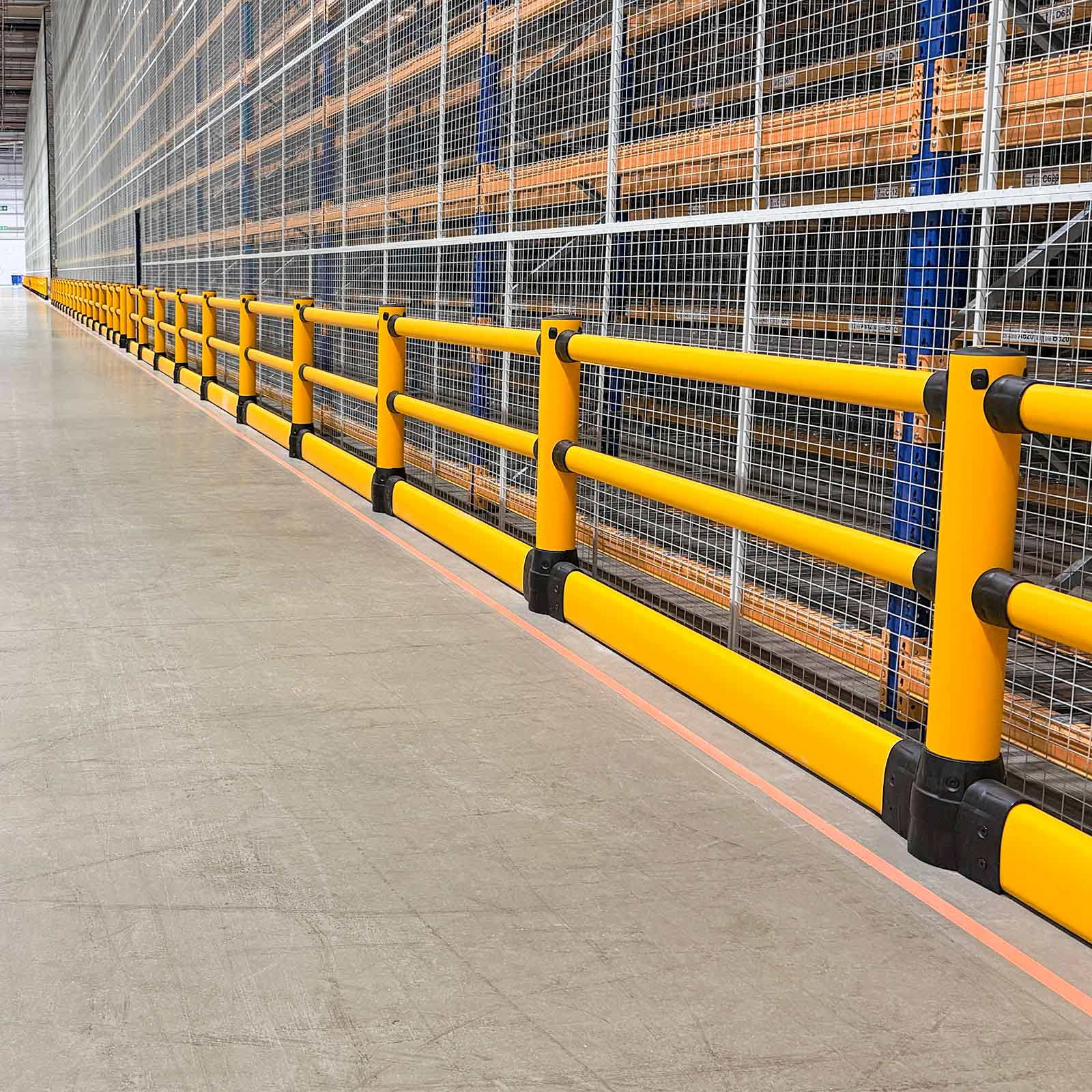 FLEX+ Pedestrian with Ground Guard running along mesh-fronted racking in a warehouse aisle, shielding it from forklifts.