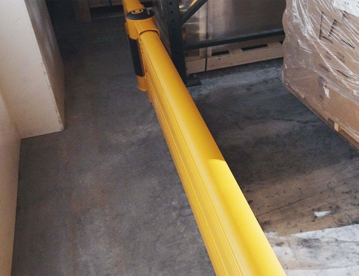 Overhead view of a GroundBarrier Double run along the base of pallet racking beside a wall.