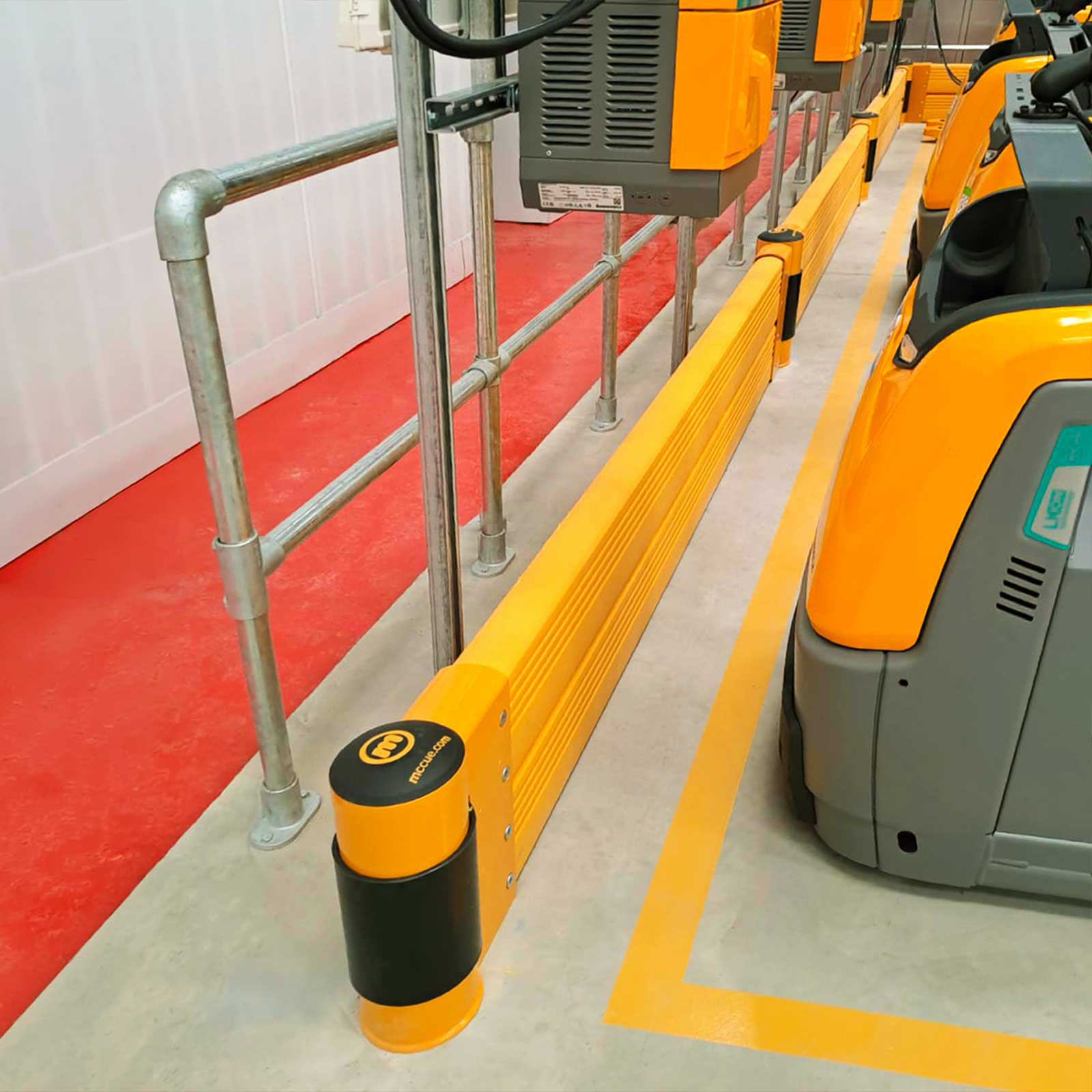 GroundBarrier Double run between a steel handrail and a row of electric pallet trucks at charging stations in a warehouse.