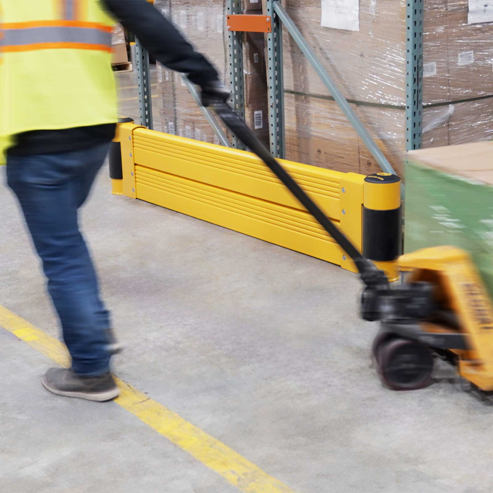 GroundBarrier Double protecting a pallet rack end as a worker pulls a loaded pallet jack past in a warehouse.