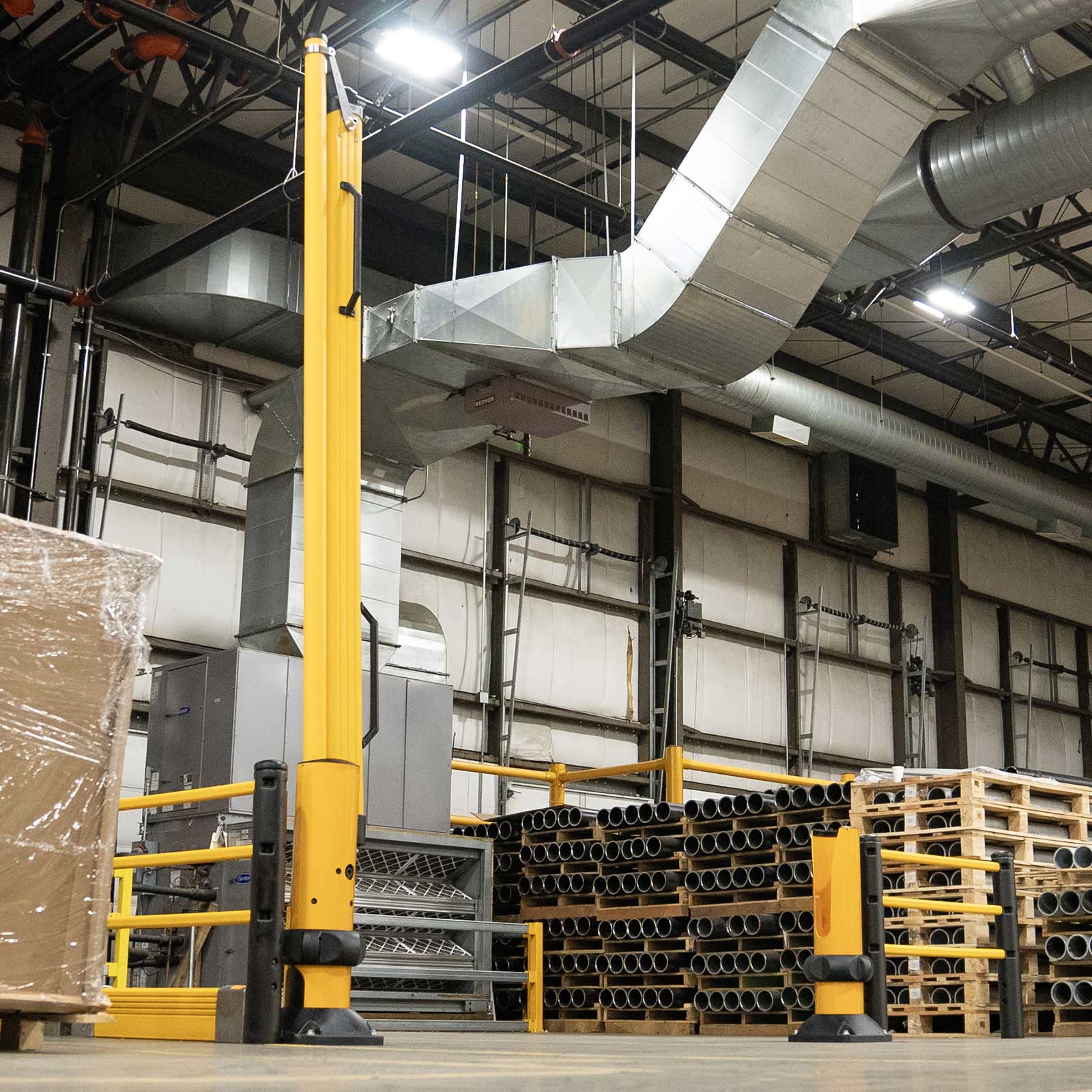 SafeStop ForkLift Gate with its rail arm raised open beside pallet stock in an industrial facility.