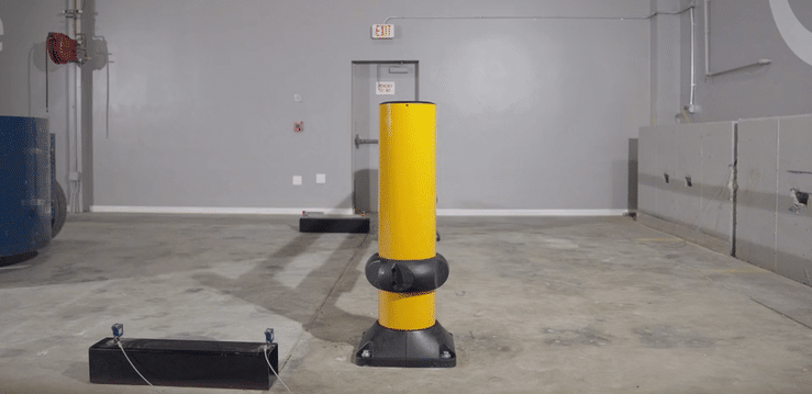 A weighted test cart striking a SafeStop ForkLift Gate post in an impact test as the base absorbs the hit.