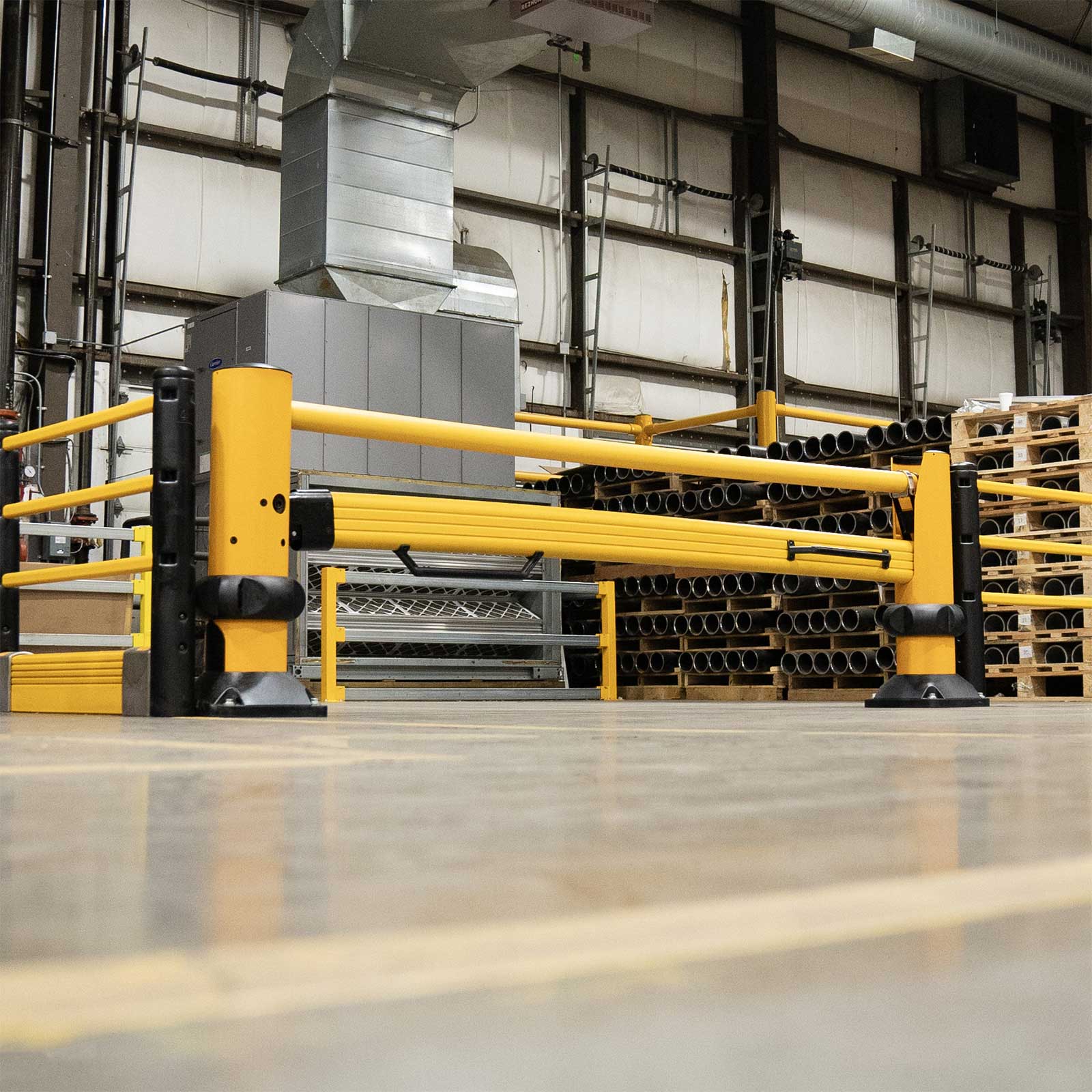 Low-angle view of a SafeStop ForkLift Gate closed across an aisle in front of stacked pallets in a warehouse.