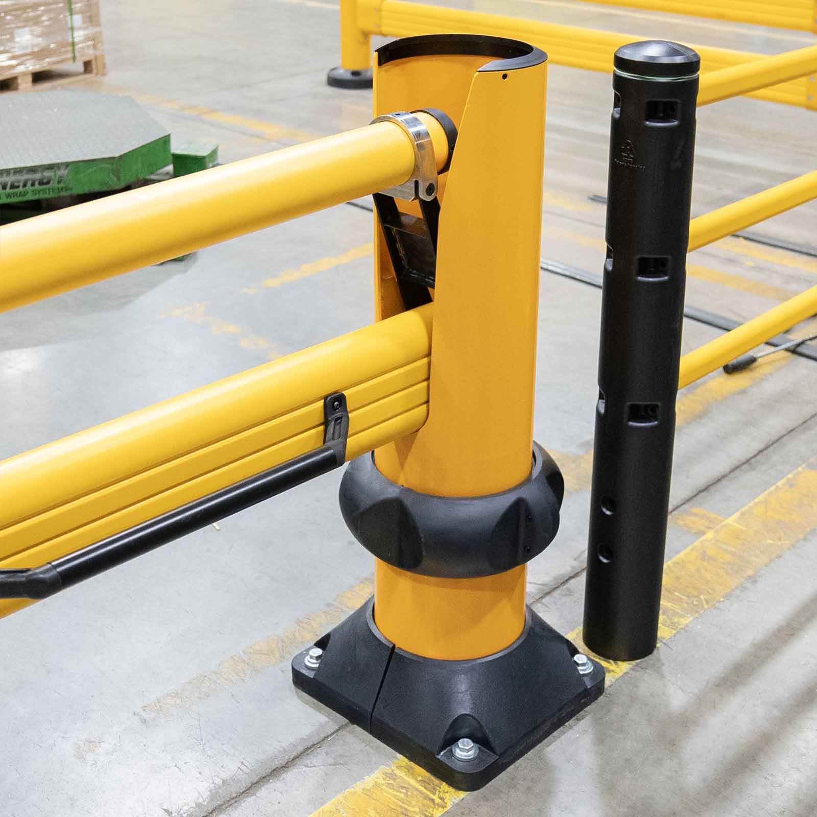 Close-up of the SafeStop ForkLift Gate rail end resting on its post beside a black post on a warehouse floor.