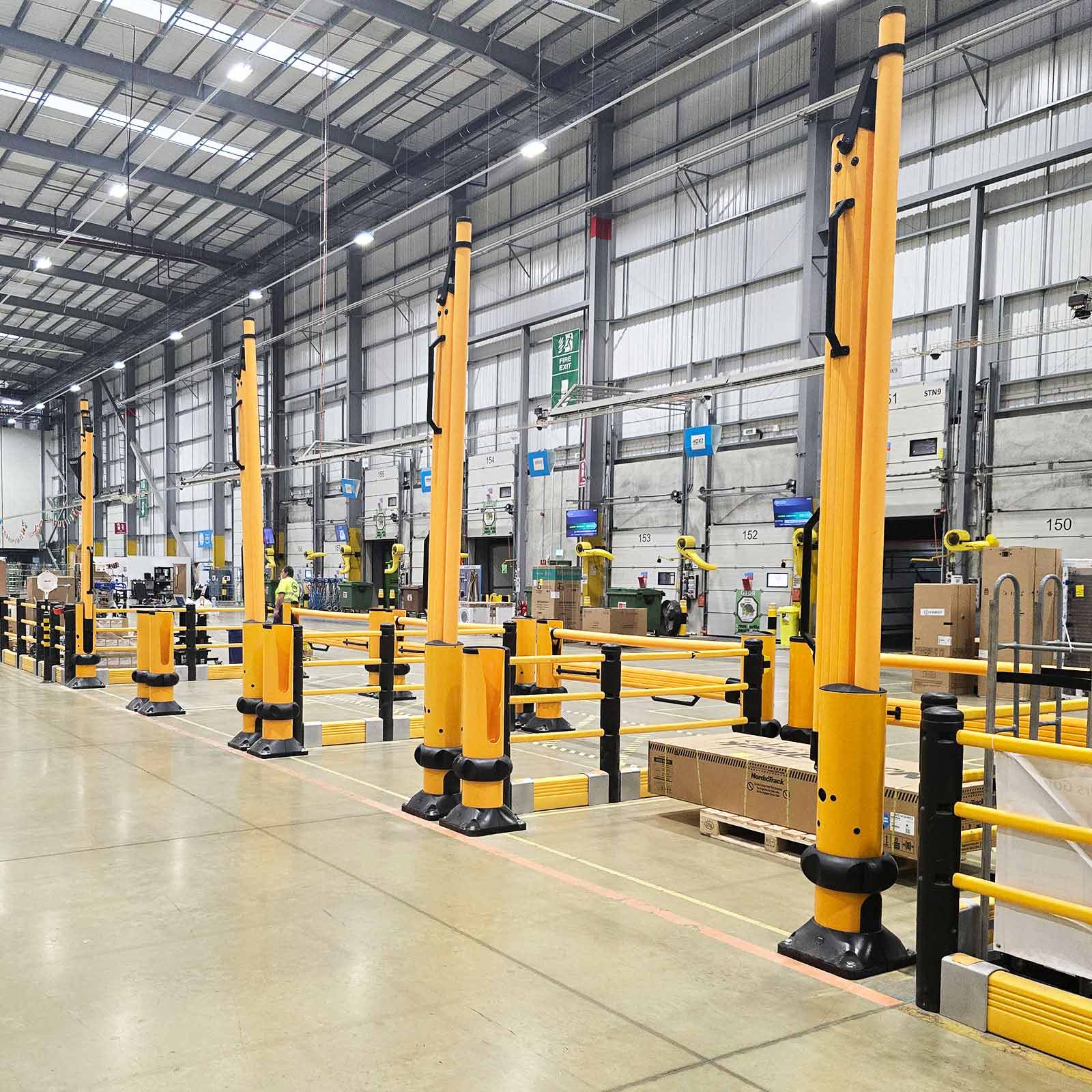 SafeStop ForkLift Gates with their rail arms raised open along a striped forklift aisle in a distribution center.