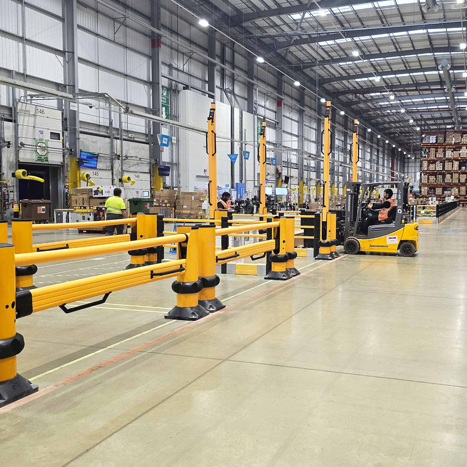A row of SafeStop ForkLift Gates guarding work bays along a forklift aisle in a distribution center.