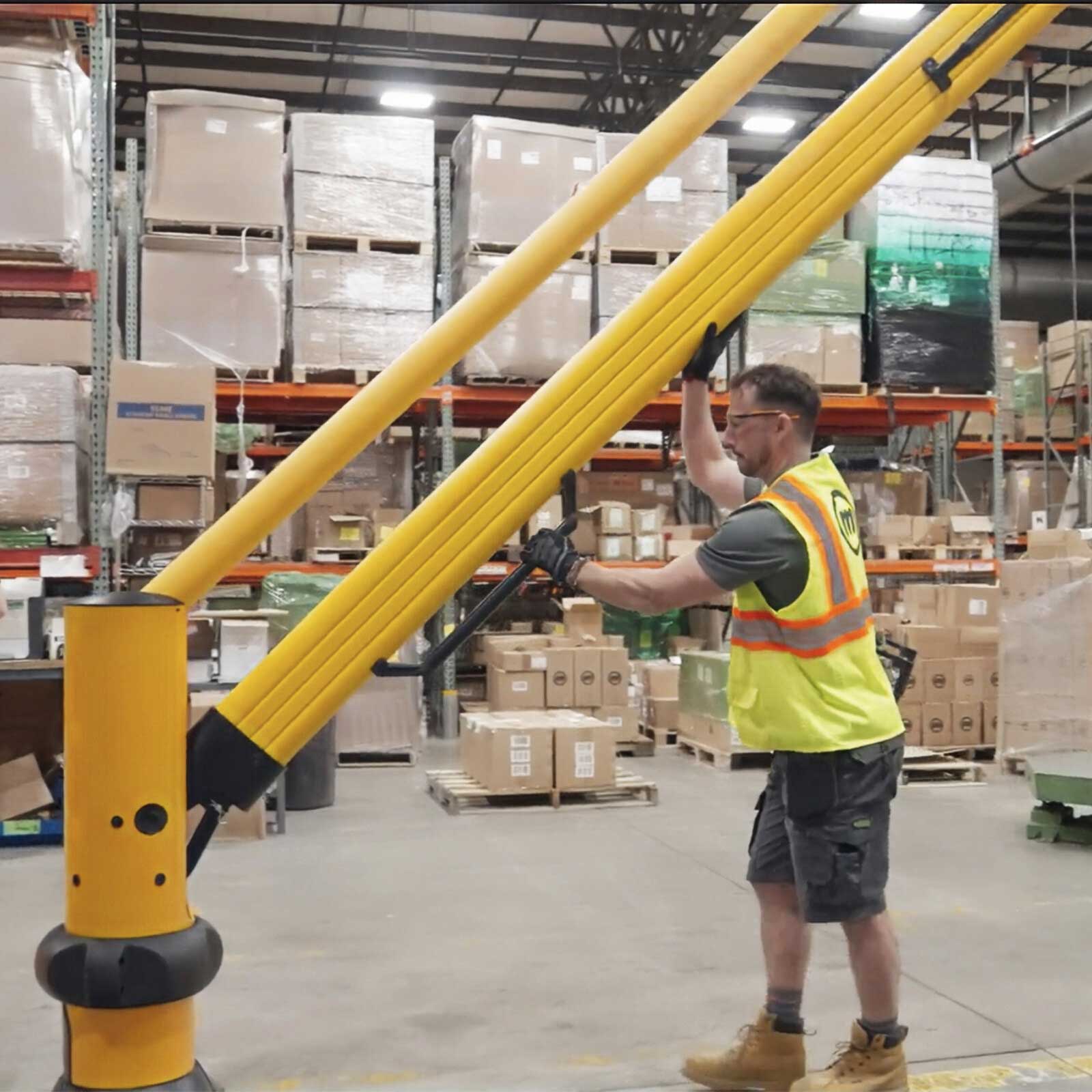 A worker in a safety vest lifting the SafeStop ForkLift Gate rail arm open with its shock-assisted lift in a warehouse.