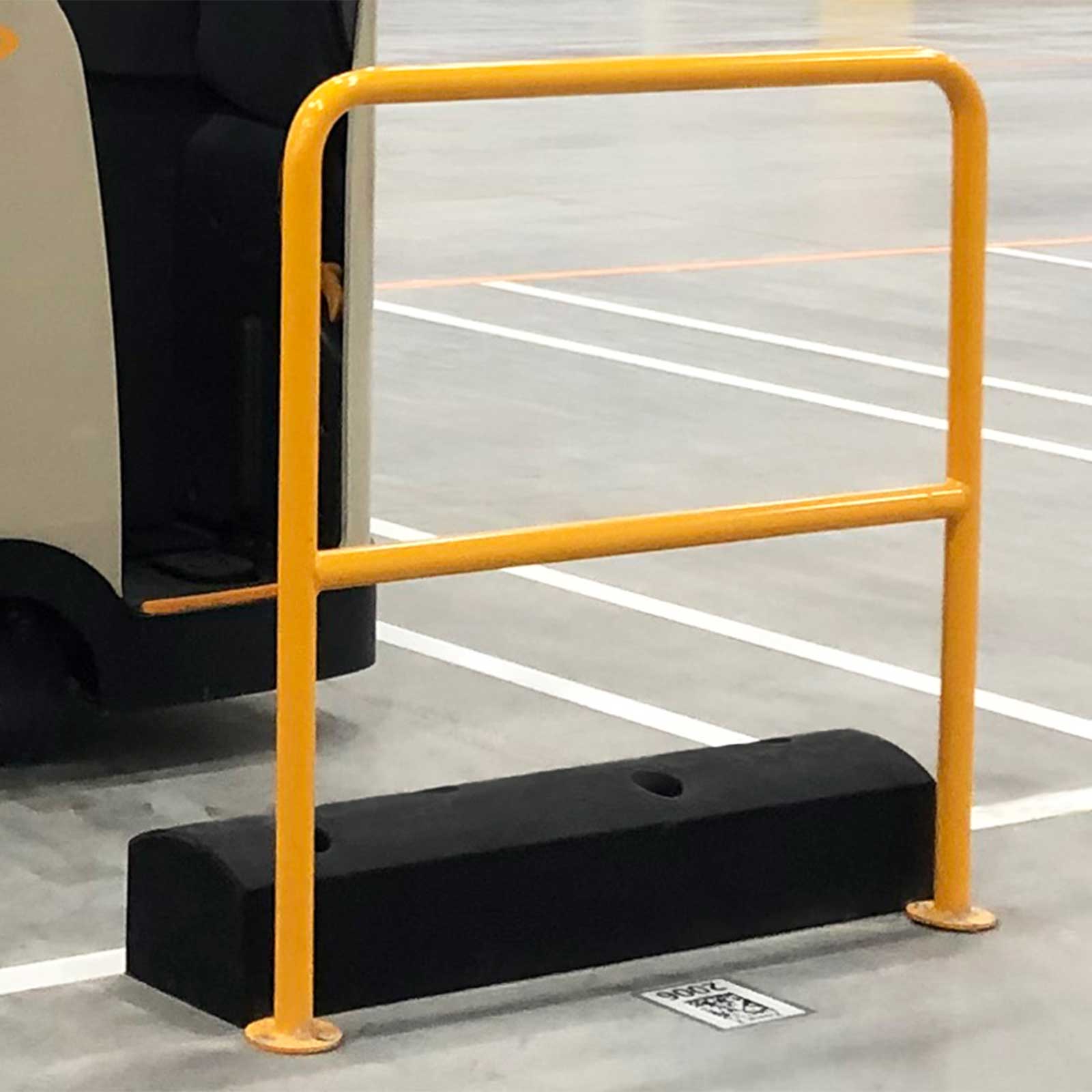 Close view of a SafeStop ForkShield at the base of a yellow rail, with a material handling vehicle parked behind it.