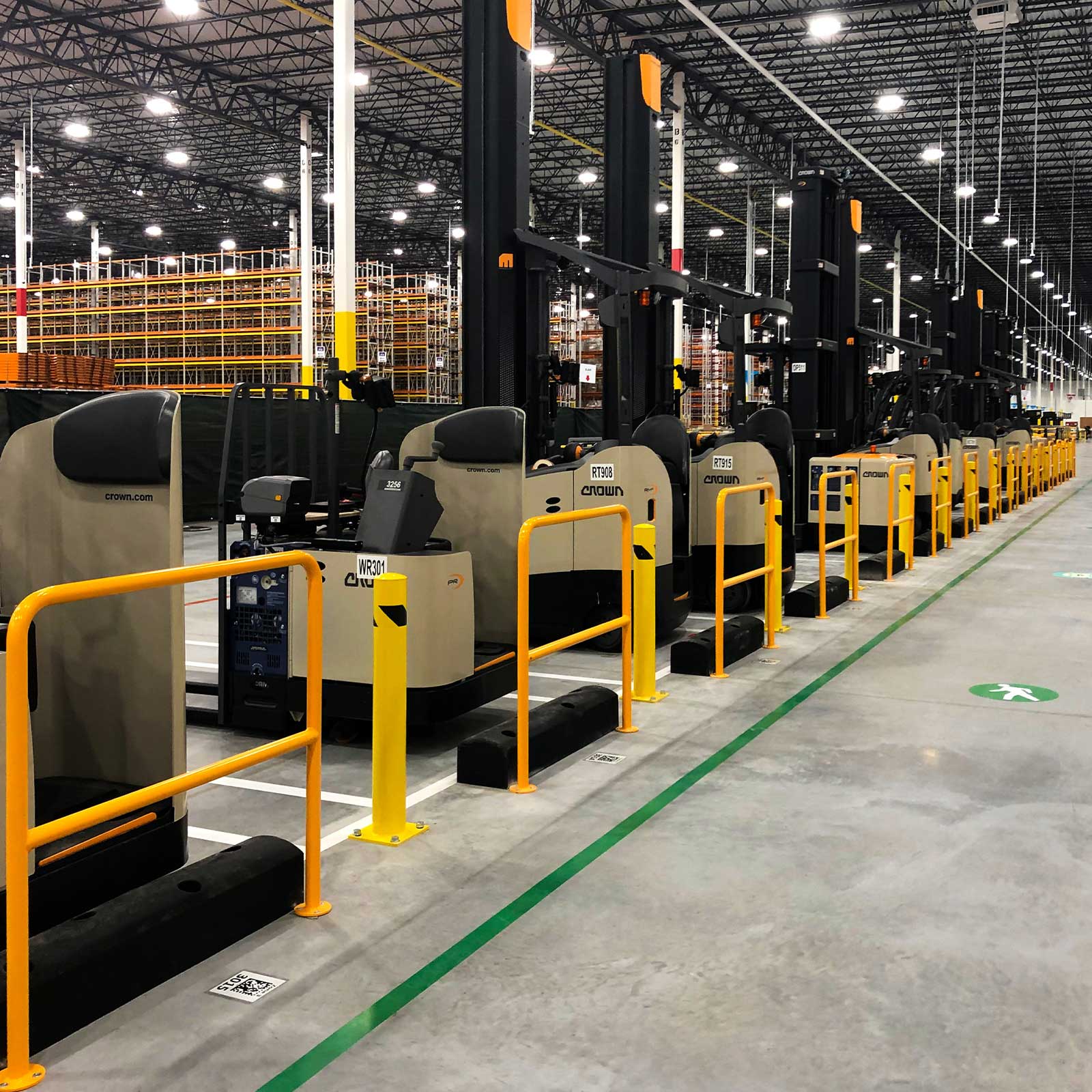 SafeStop ForkShield barriers keeping parked material handling vehicles off yellow rails and SteelPost 4's in a distribution center.