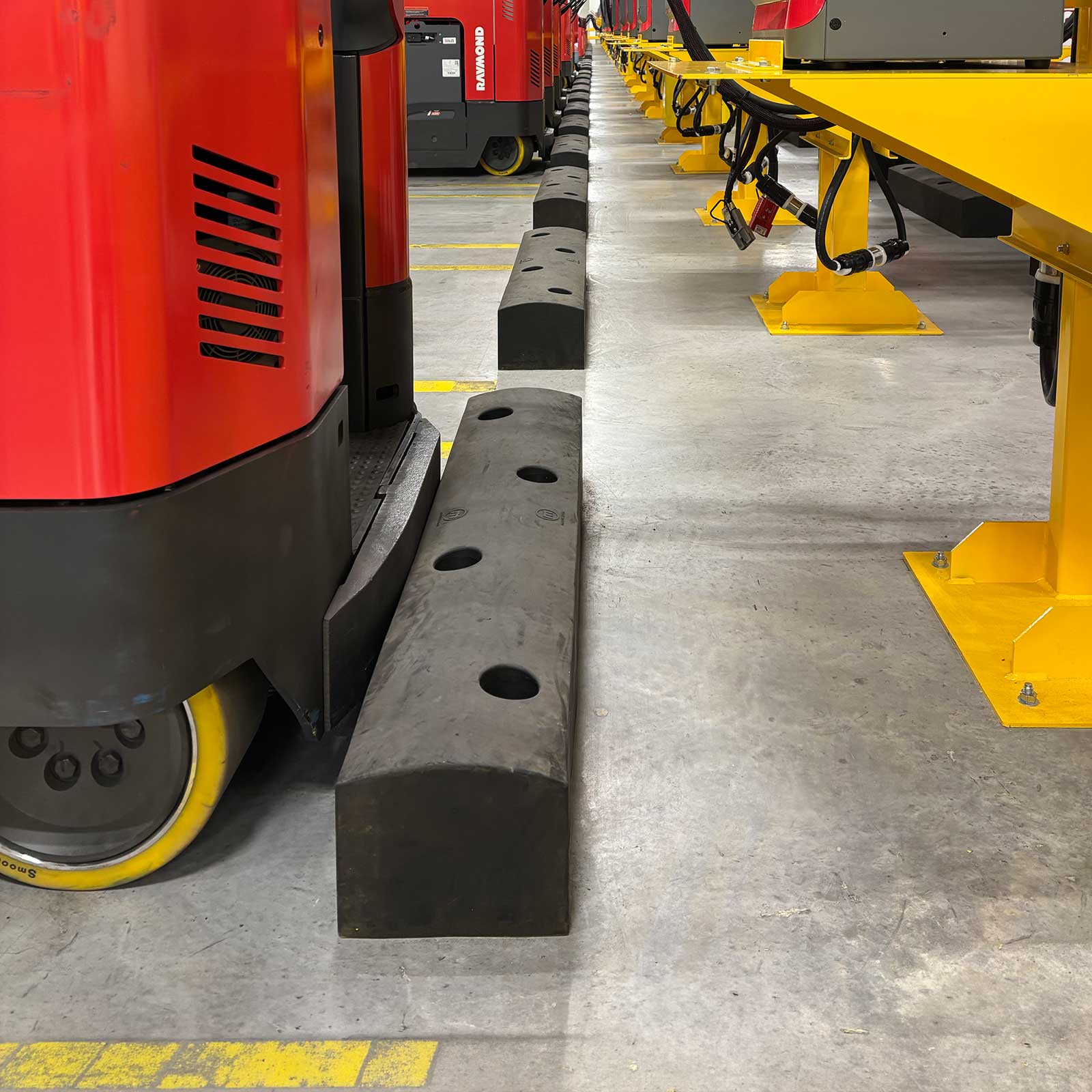 A reach truck wheel stopped against a SafeStop ForkShield shock-absorbing barrier in a warehouse.