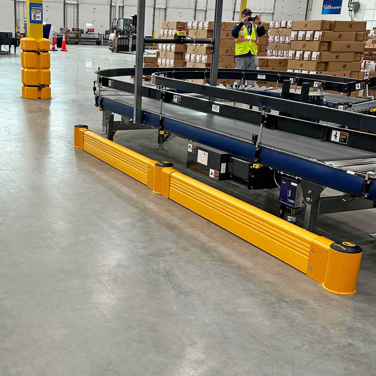 SafeStop GroundBarrier run protecting the base of a conveyor line in a warehouse.