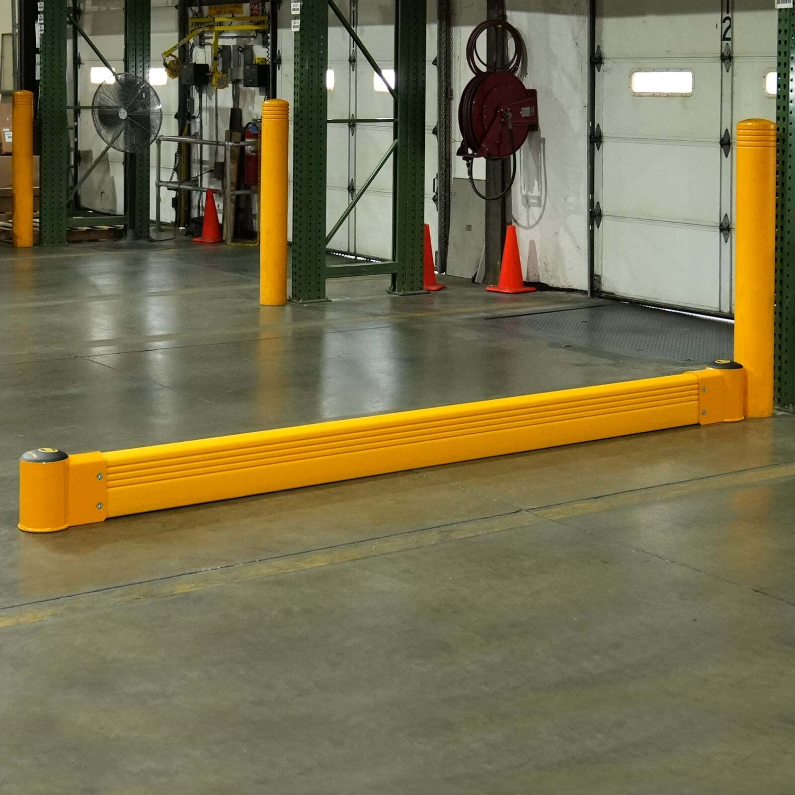 SafeStop GroundBarrier run between two yellow FlexCore bollards in front of loading dock doors.