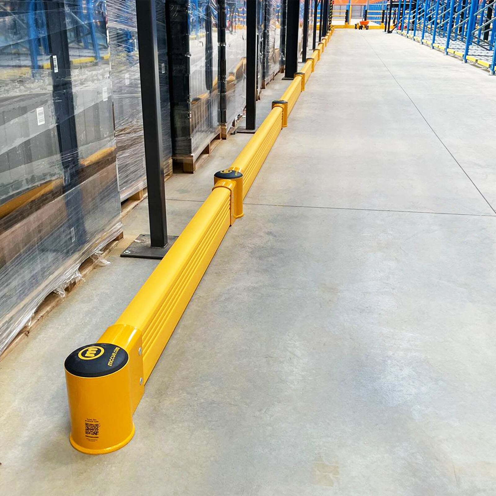 Long SafeStop GroundBarrier run along a warehouse aisle, shielding stretch-wrapped pallets and racking.