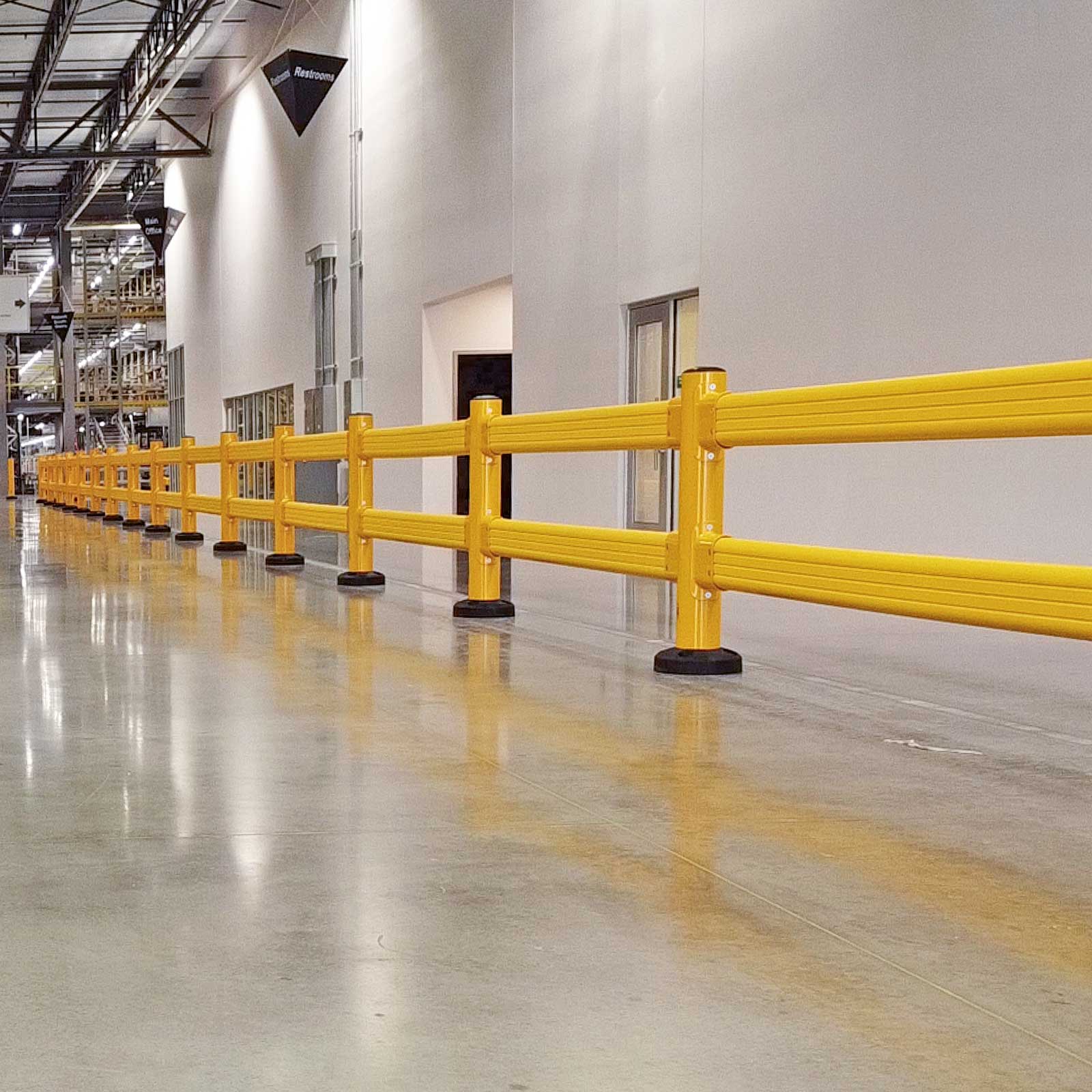 SafeStop GuardRail run along the wall of a long warehouse corridor past office doors.