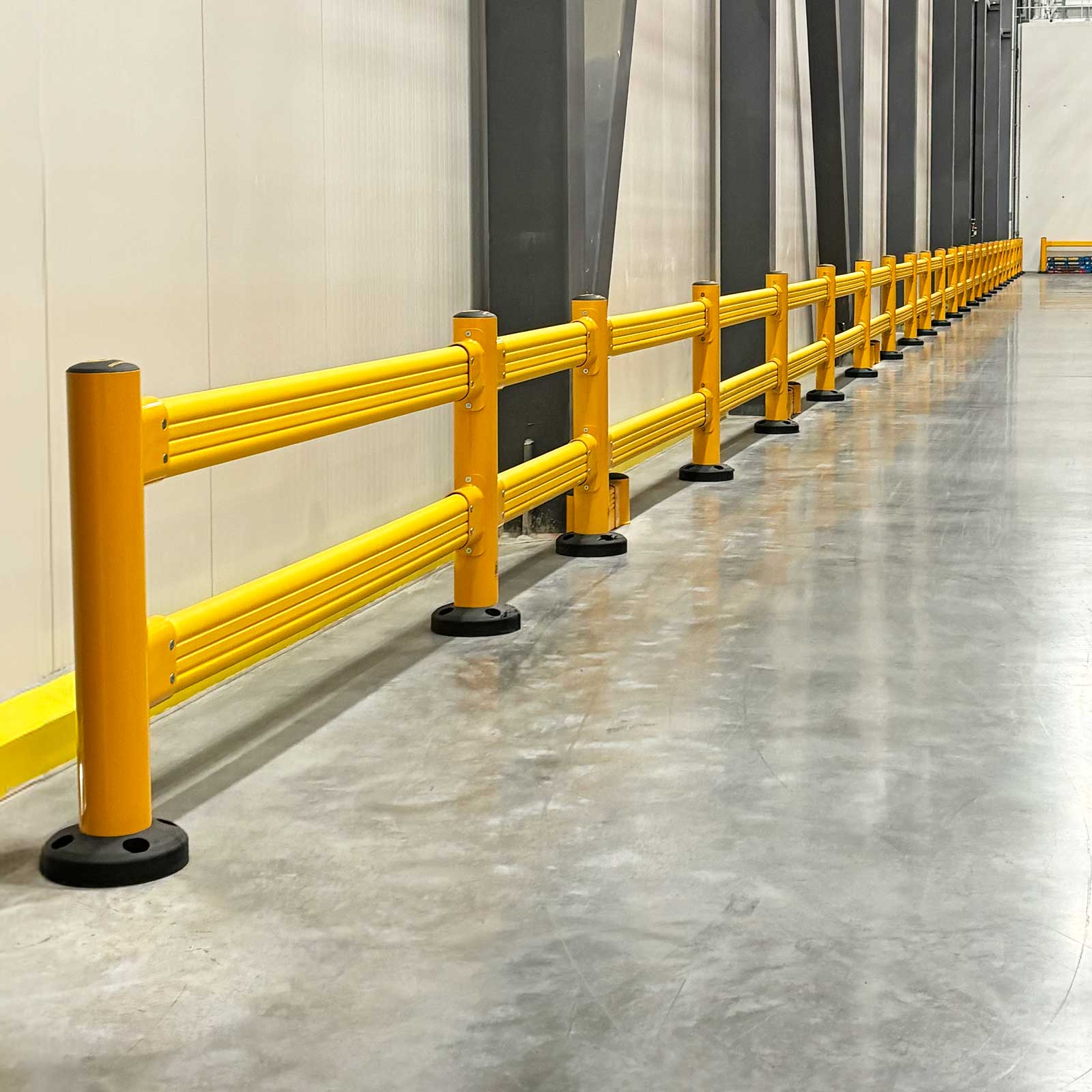 SafeStop GuardRail run along a warehouse wall lined with steel columns.