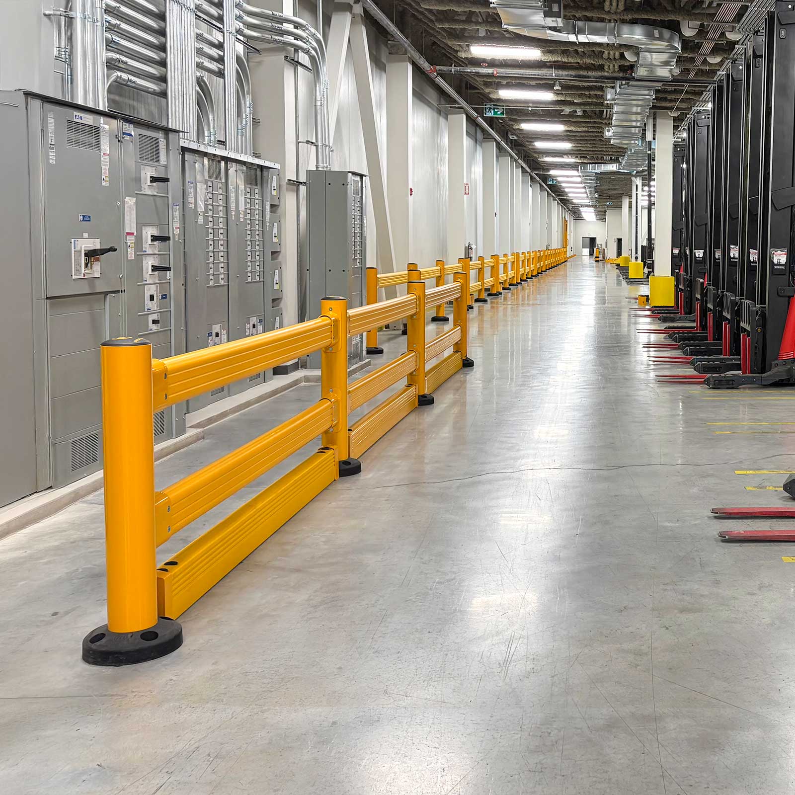 SafeStop GuardRail with FloorGuard along a row of electrical panels, forklifts parked across the aisle.
