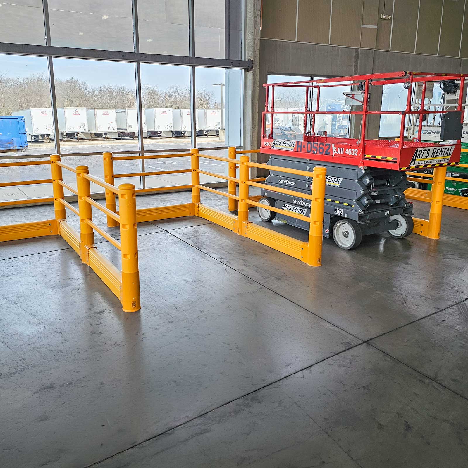 SafeStop Pedestrian with GroundBarrier runs forming a walkway beside a parked scissor lift in an industrial facility.