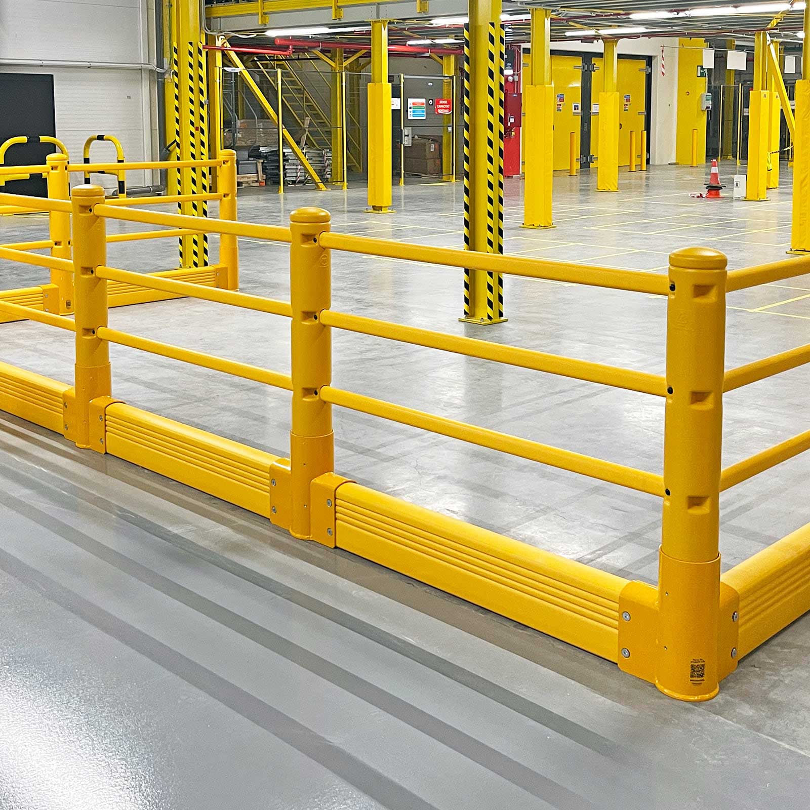 SafeStop Pedestrian with GroundBarrier impact-rated pedestrian barrier forming a corner run in a warehouse.