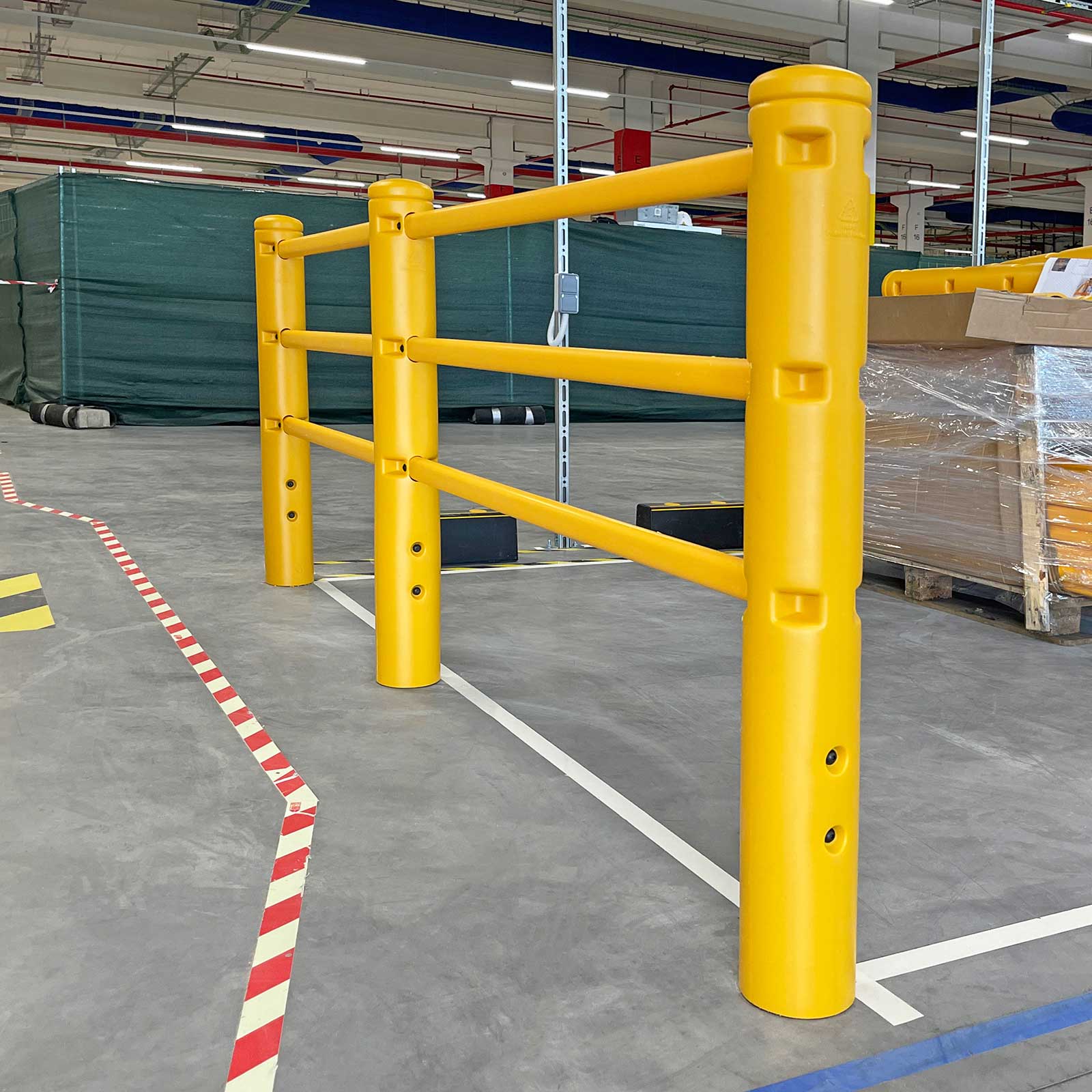 SafeStop PedestrianBarrier end post and three rails beside red-and-white floor markings in a distribution center.