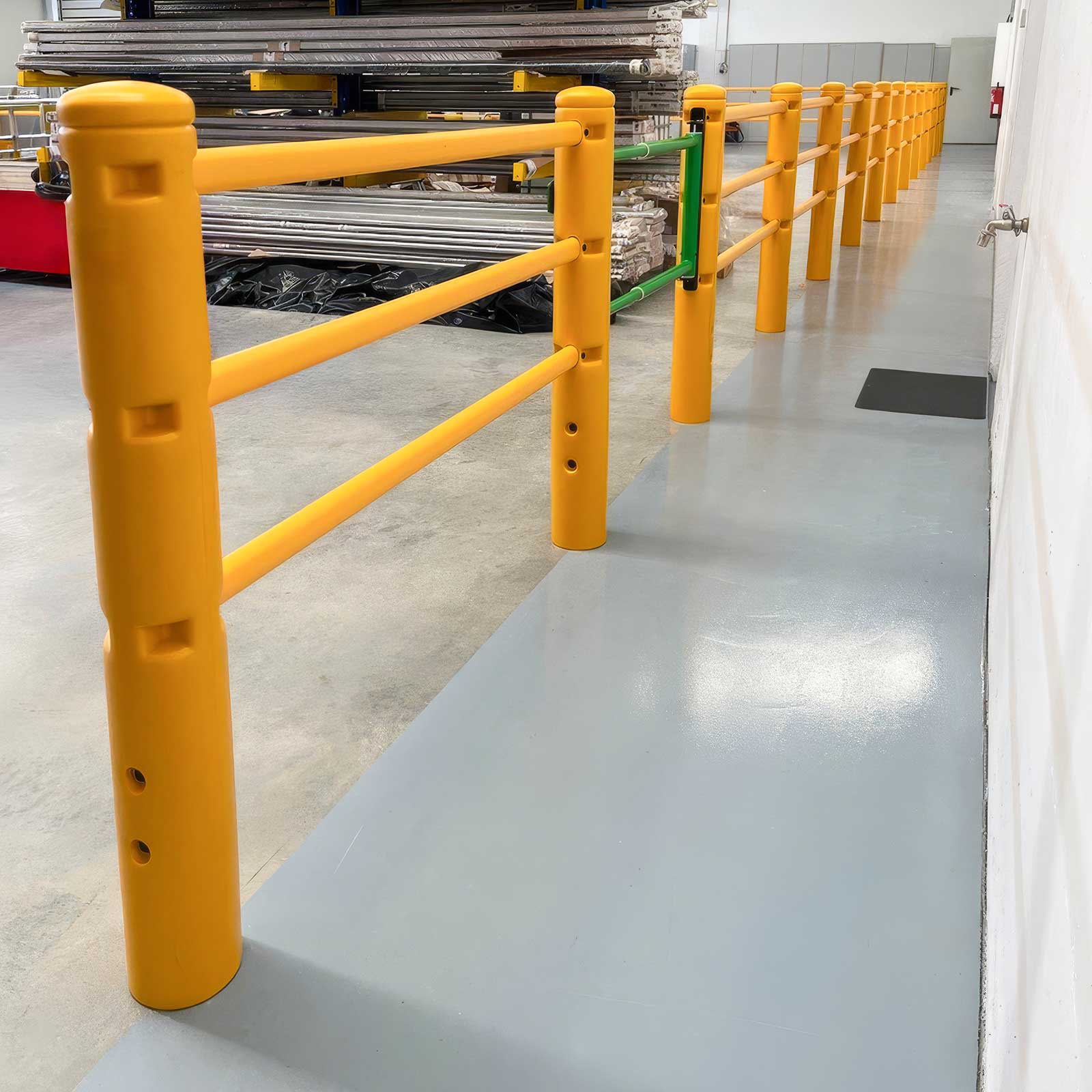 SafeStop PedestrianBarrier pedestrian walkway barrier with a green swing gate, lining a grey walkway beside stock racking.