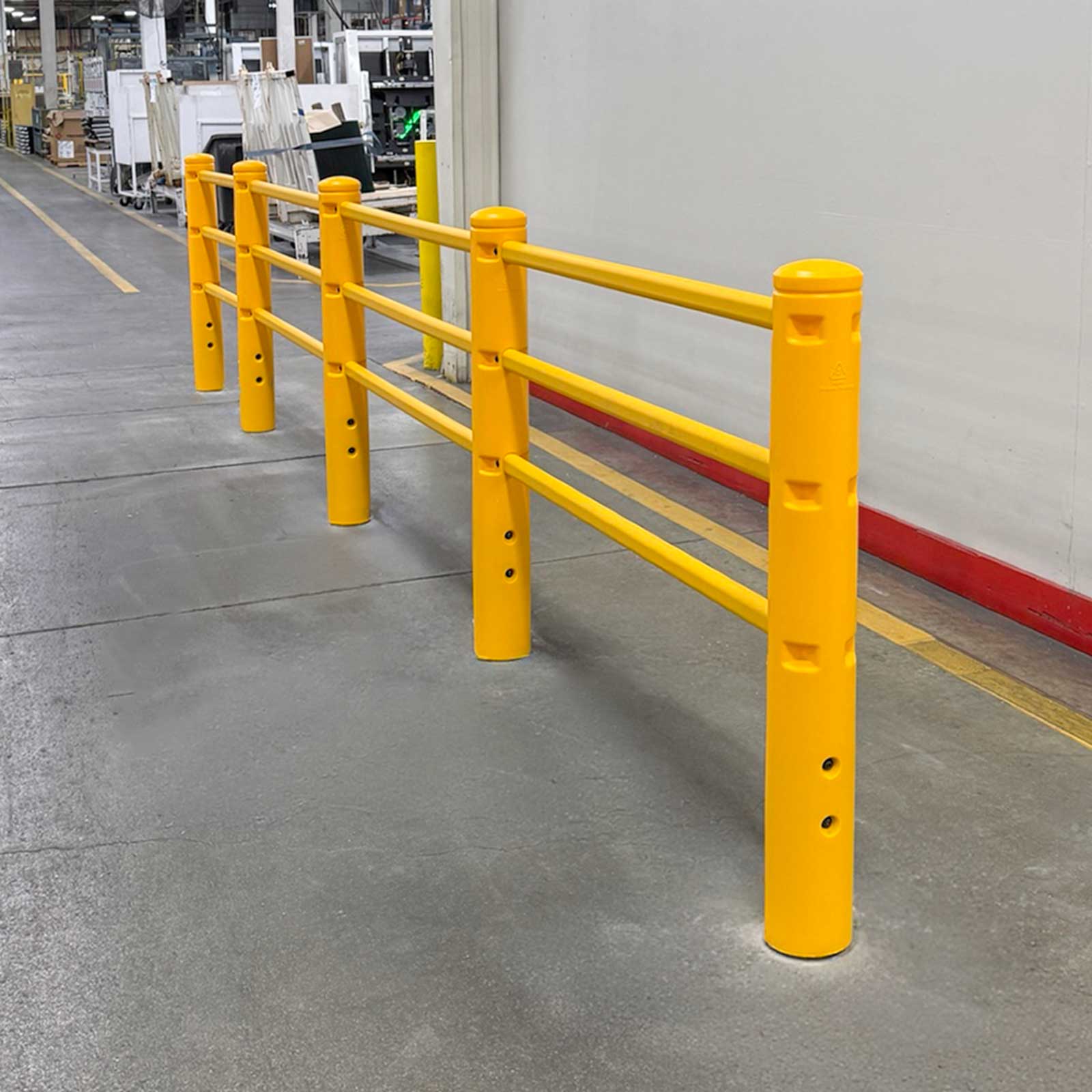 SafeStop PedestrianBarrier lining a walkway along a plant wall, with a yellow floor line and production area beyond.