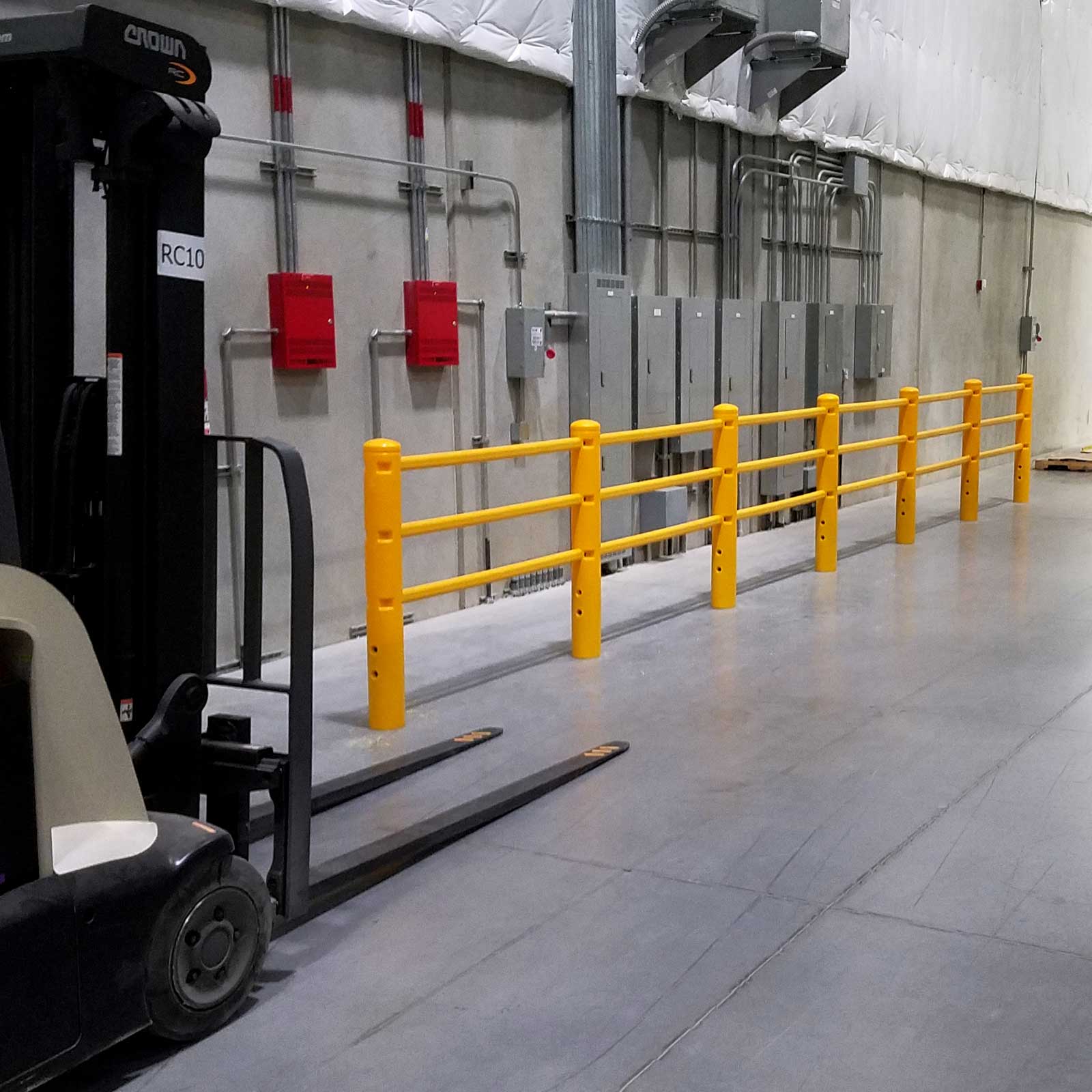 SafeStop PedestrianBarrier along a warehouse wall with fire equipment, a parked forklift in the foreground.