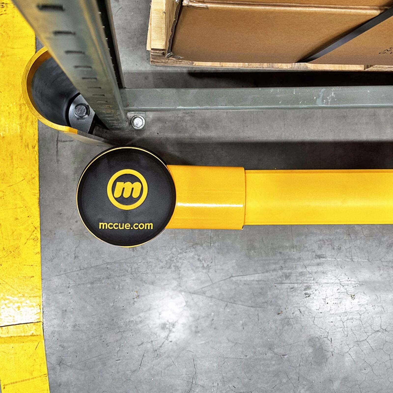 Overhead view of a SafeStop RackEnd Protector Double end post with a McCue logo cap beside a rack upright.