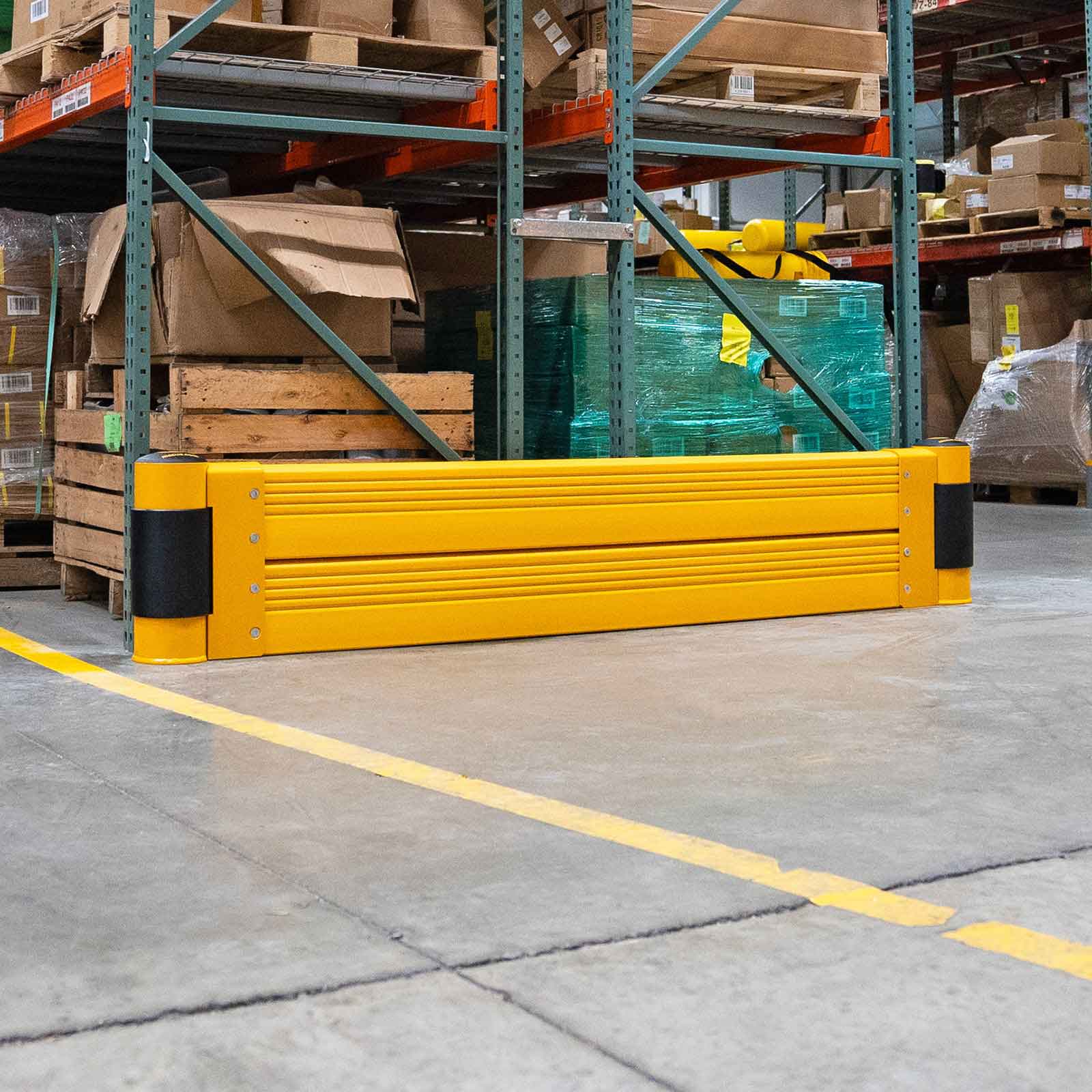 SafeStop RackEnd Protector Double across the end of a pallet rack beside a striped warehouse aisle.