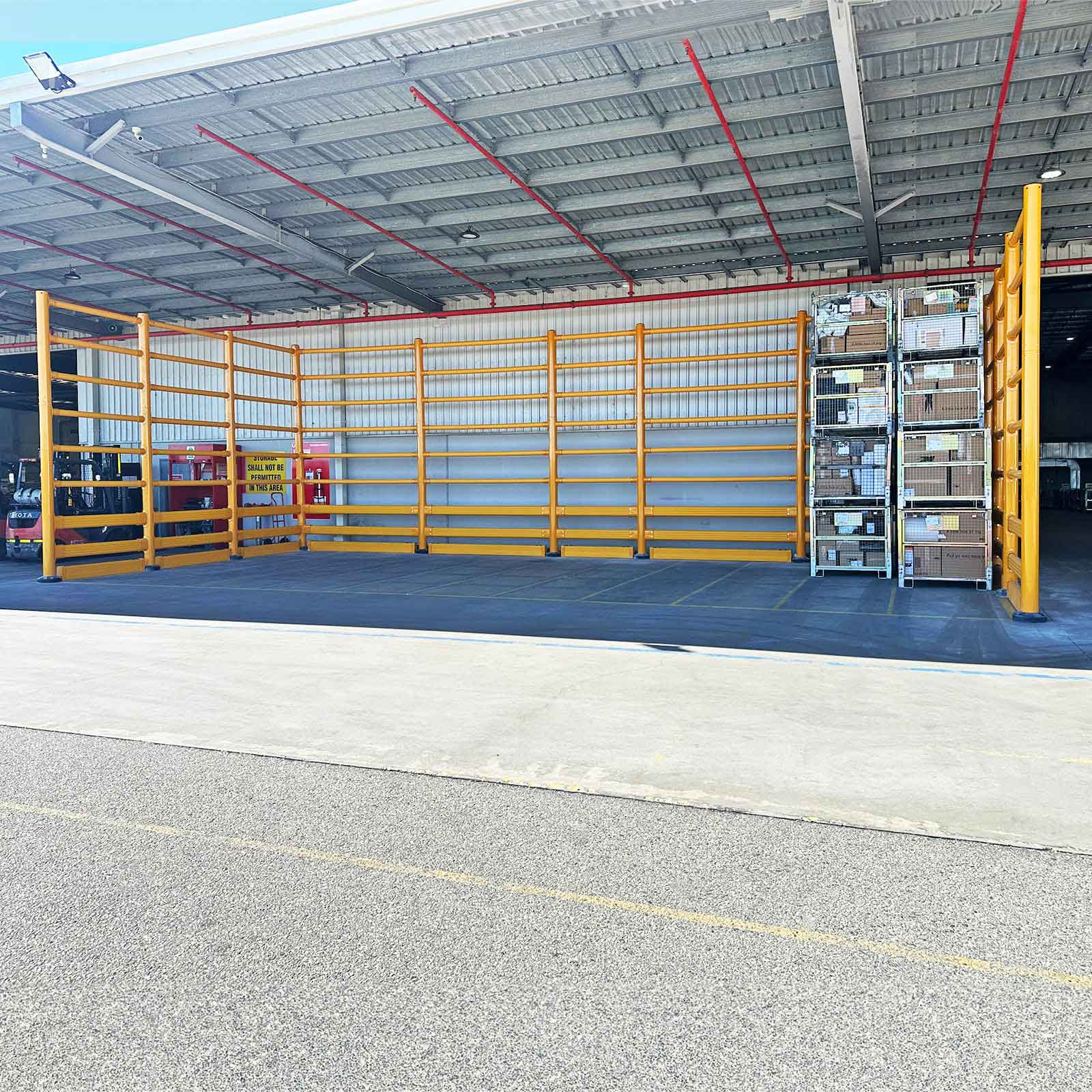 SafeStop ToppleBarrier 176 enclosing a covered outdoor storage area and racking beside a loading yard.