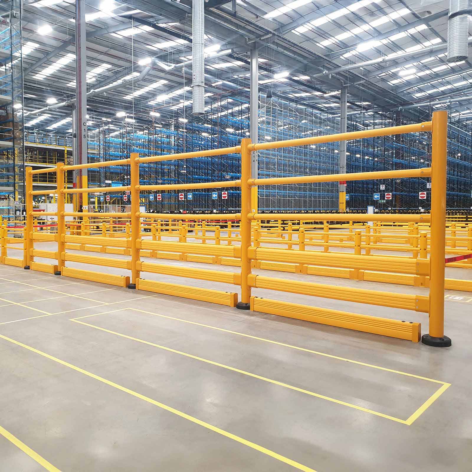A long run of SafeStop ToppleBarrier warehouse safety barriers lining a marked forklift aisle in a distribution center.