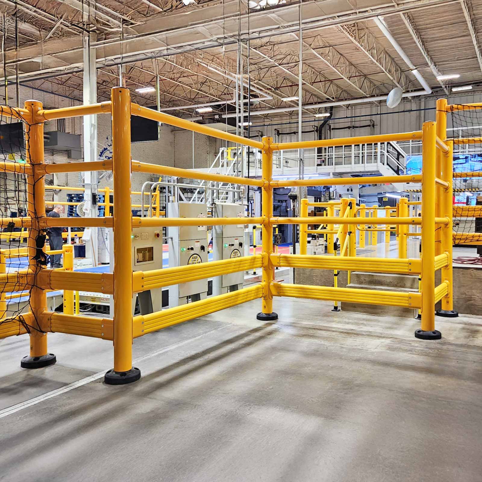 SafeStop ToppleBarrier with netting guarding packaging machinery from forklift traffic in a manufacturing facility.