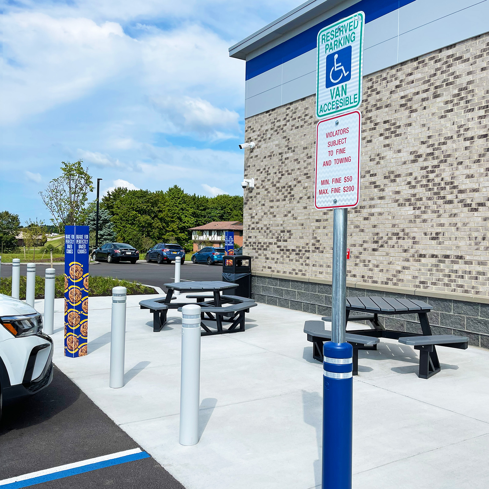 CrashCore Bollard S15 bollards with accessible parking sign covers beside a building's outdoor seating area.