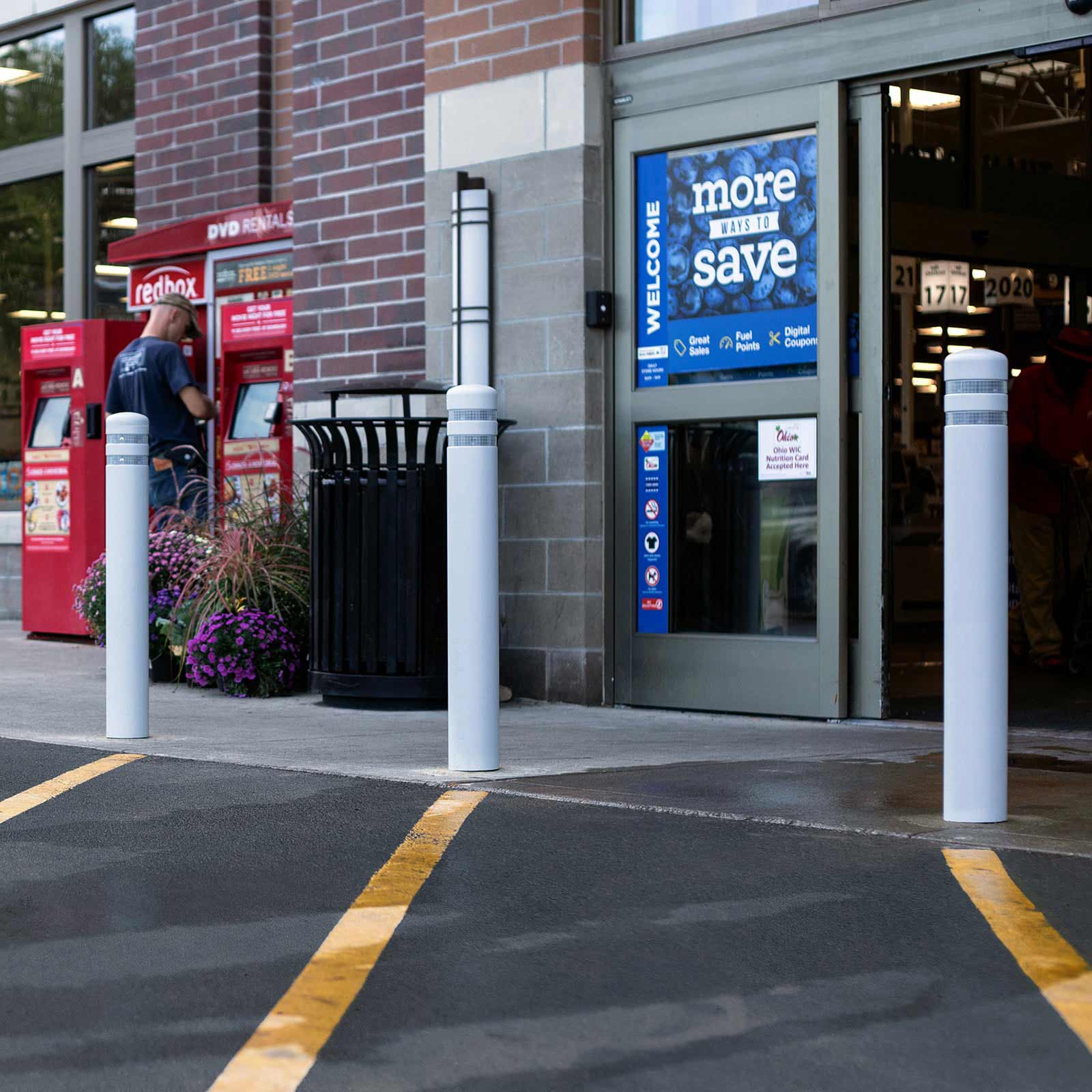 Grey CrashCore Bollard S15 bollards protecting a retail storefront entrance beside the curb.