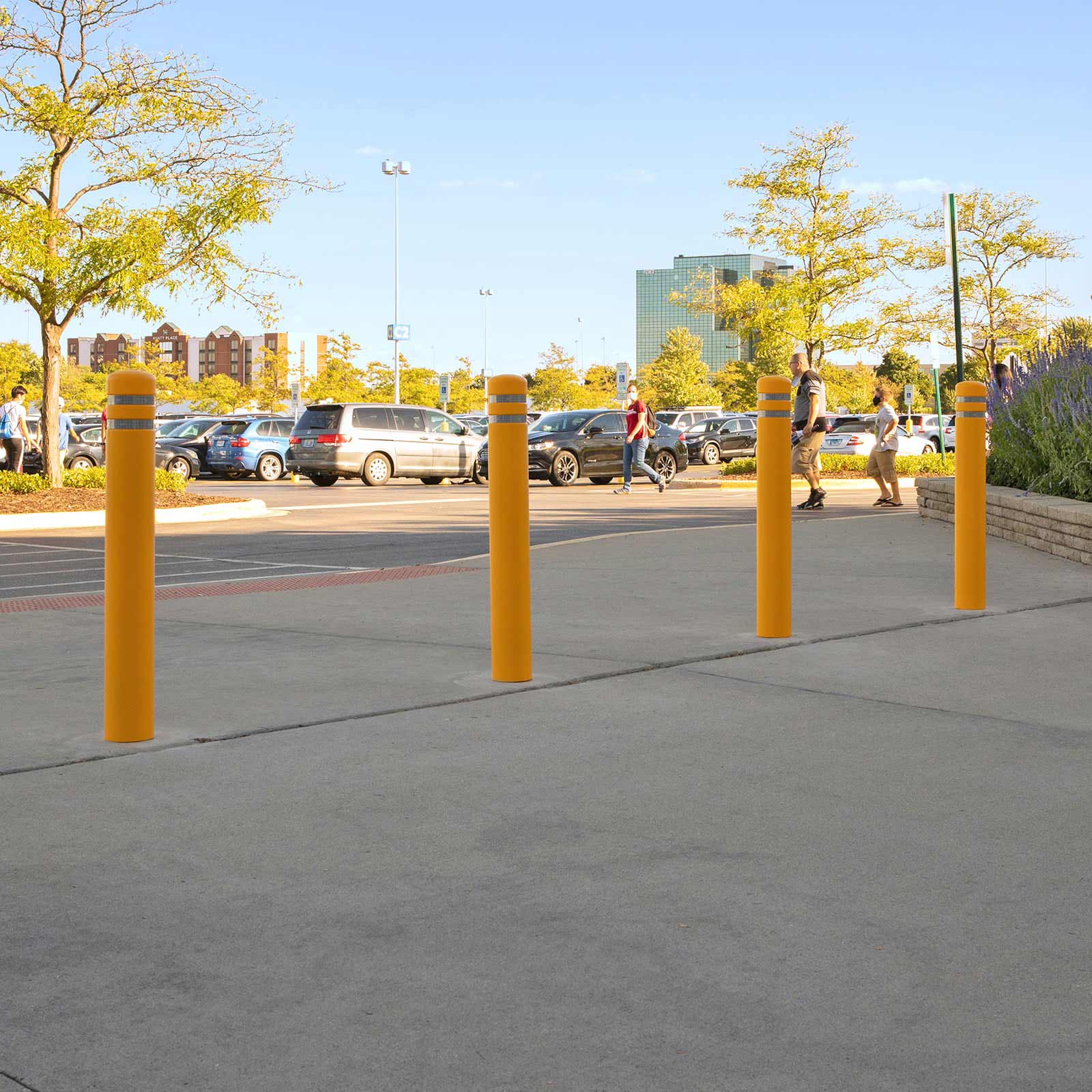 Yellow CrashCore Bollard S15 bollards protecting a walkway from parking lot traffic outside a commercial building.