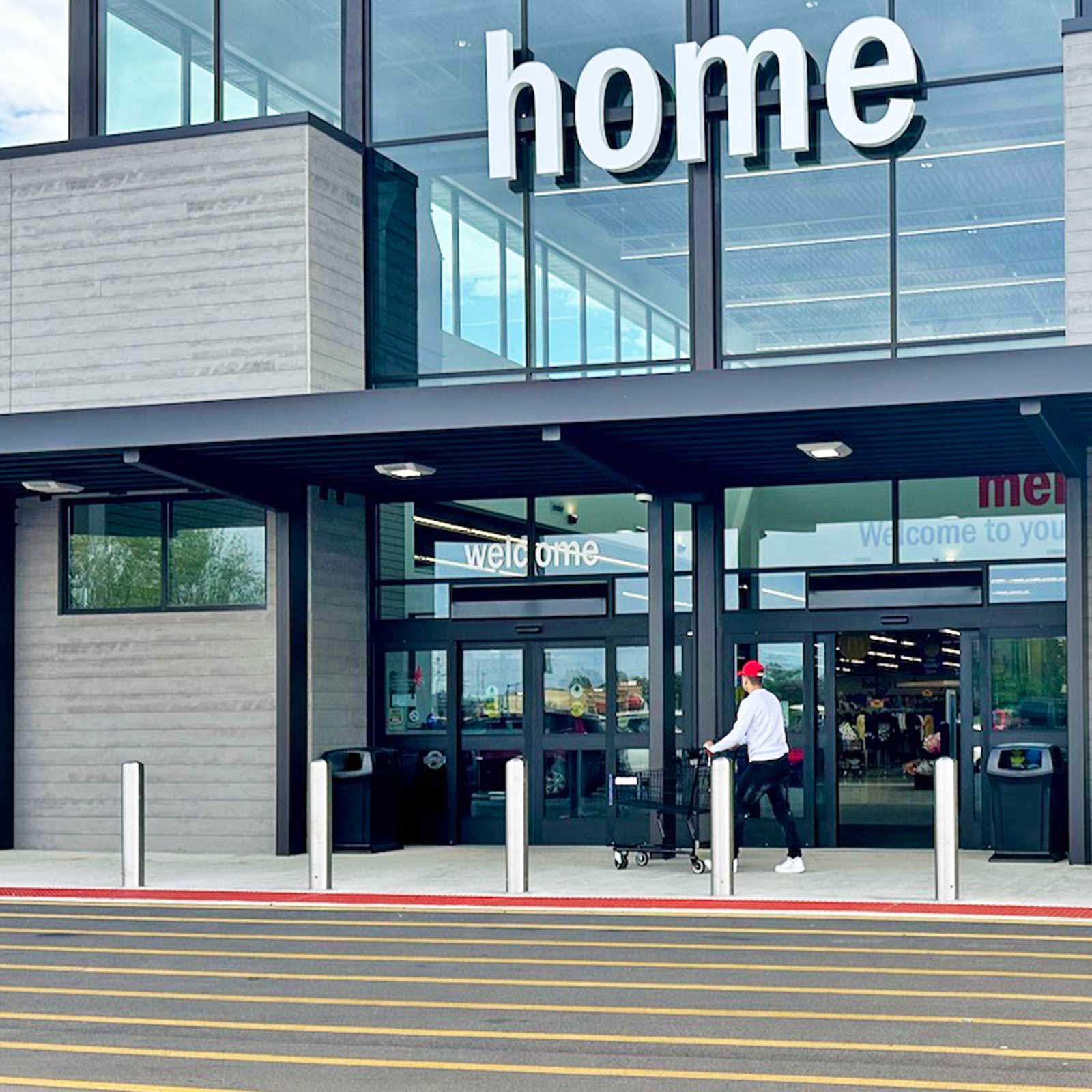 CrashCore Bollard S20 bollards protecting a retail store entrance as a shopper walks in with a cart.