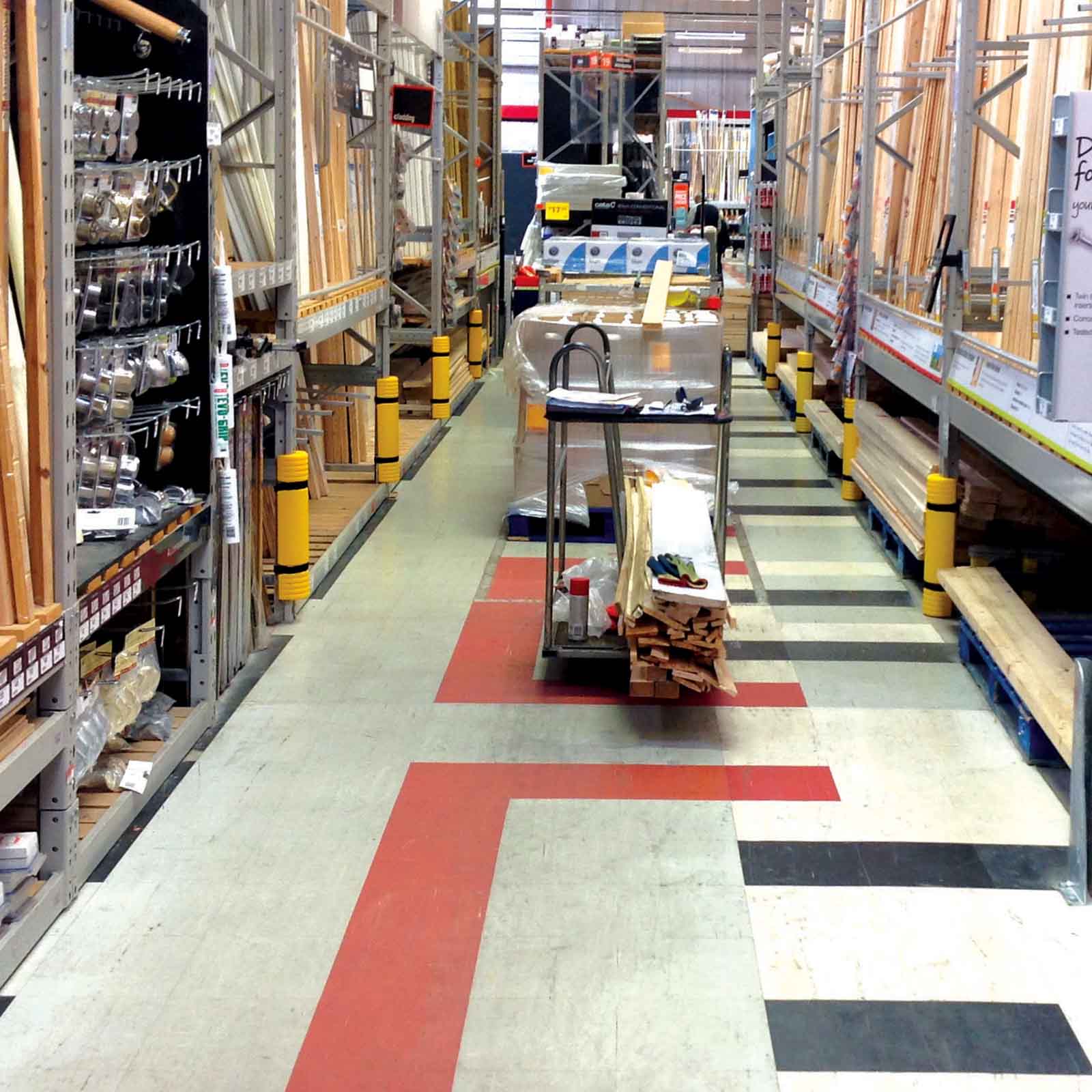 Rack Mounted Guards on rack uprights along a retail store aisle stocked with lumber.