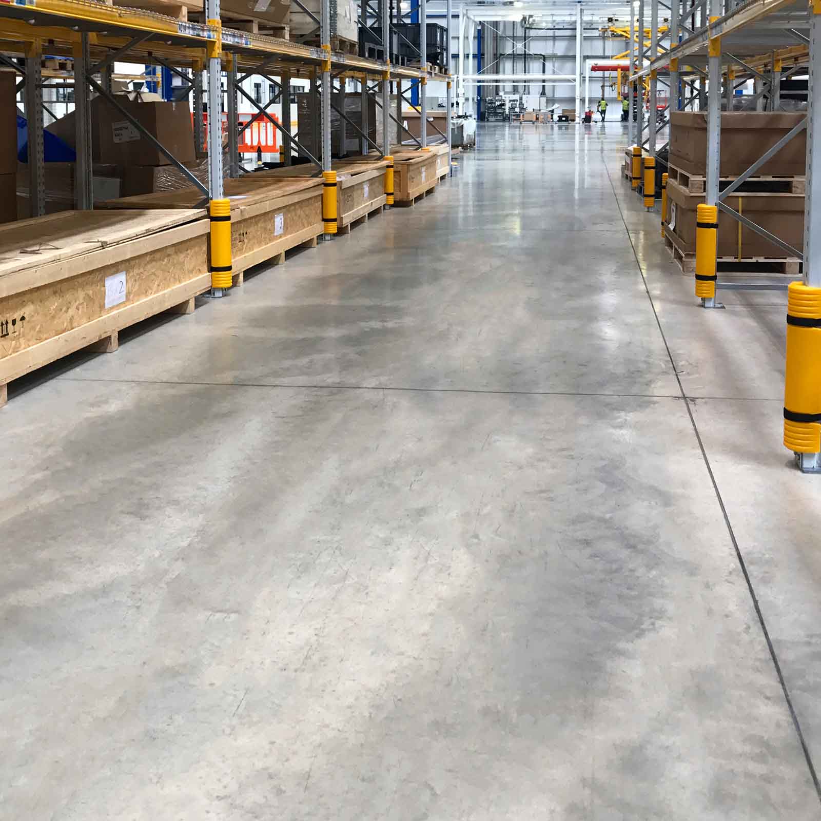 Rack Mounted Guards on pallet rack uprights along both sides of a wide aisle in a distribution center.